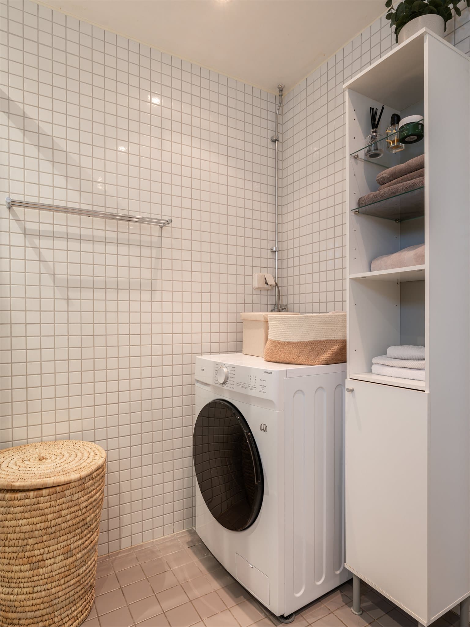 Badet er utstyrt med vegghengt toalett, servant med underskap og opplegg for vaskemaskin, som effektivt utnytter plassen.