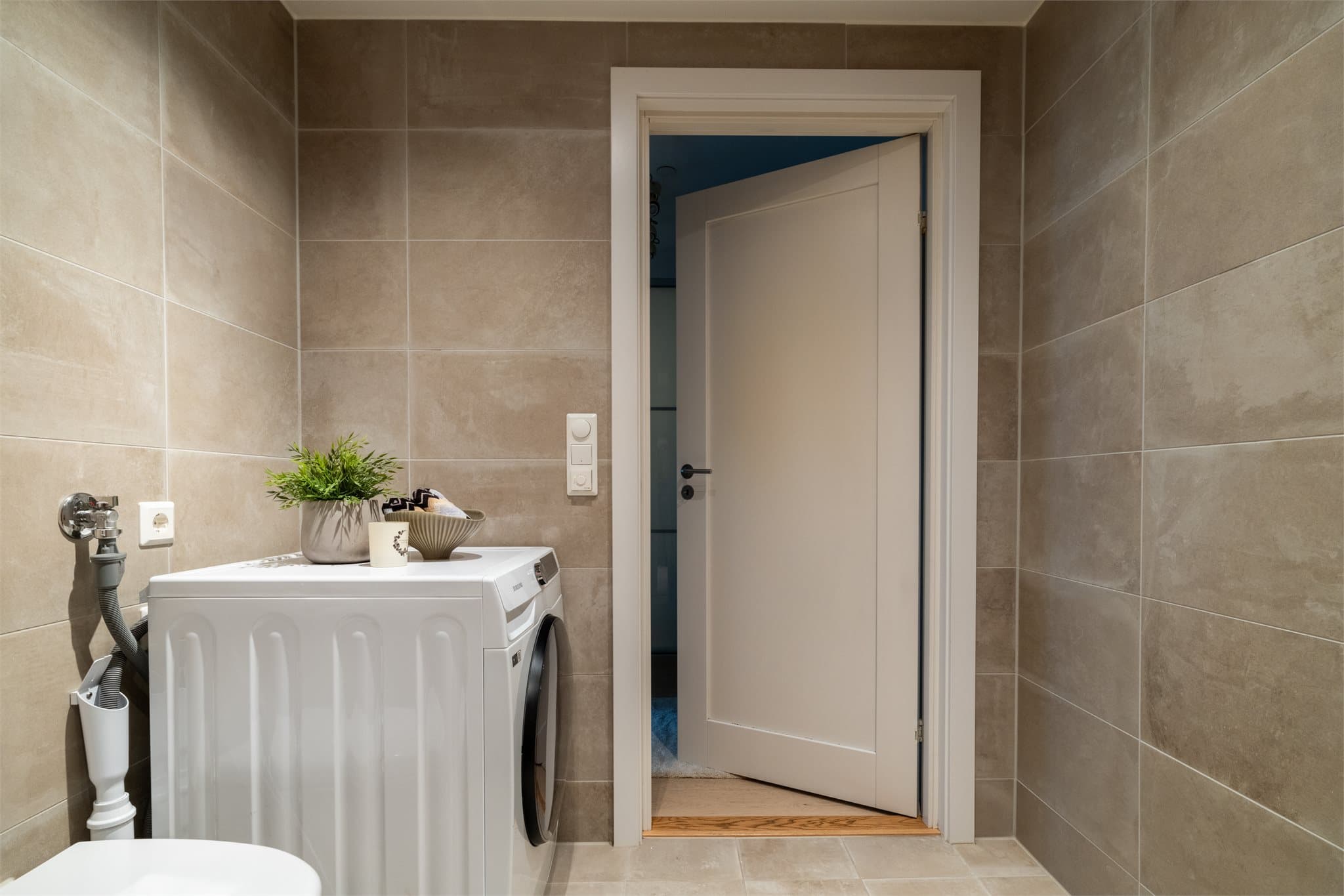 Videre har man veggmontert toalett og opplegg for vaskemaskin.