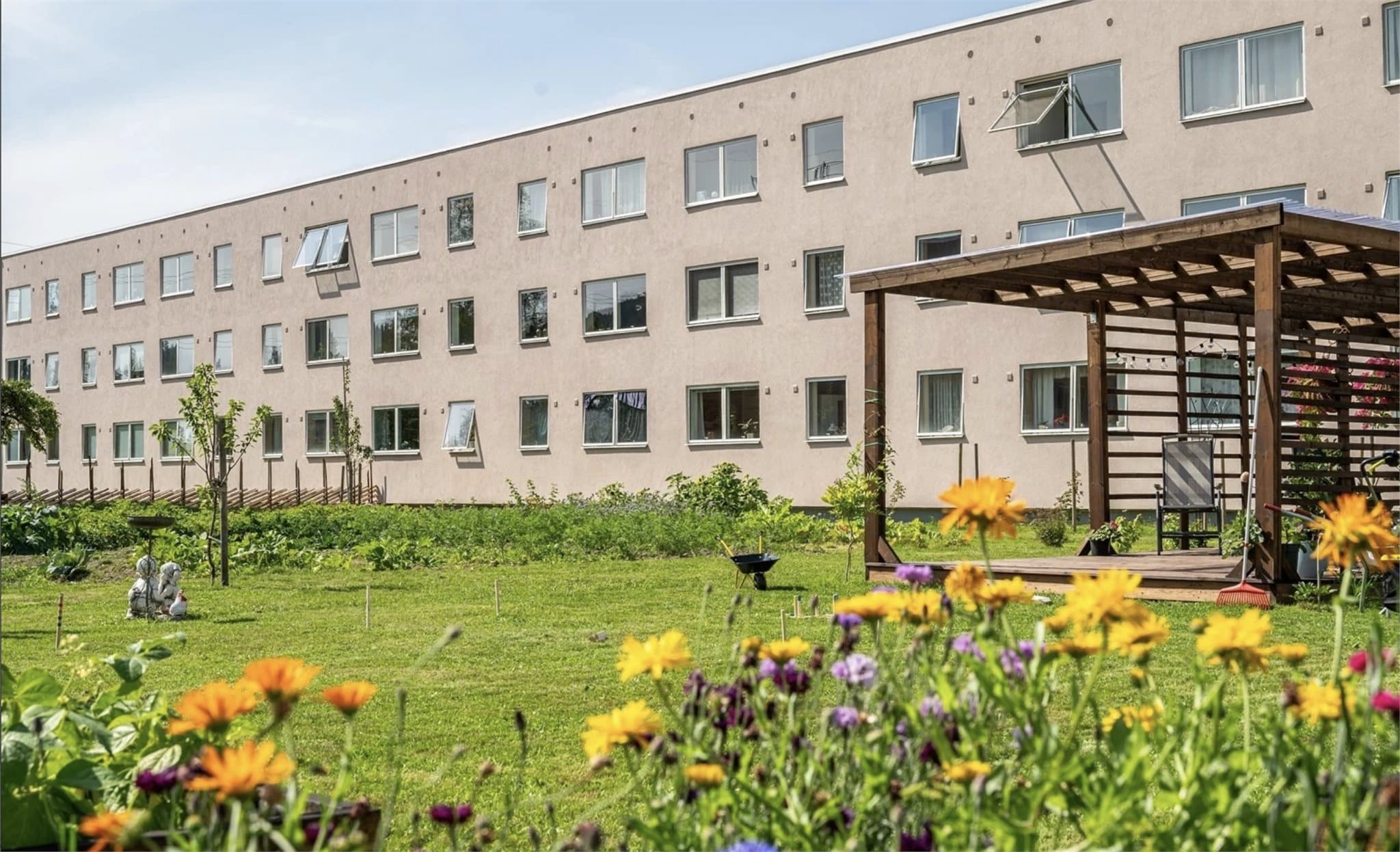 Utsyn fra kjøkken til borettslagets opparbeidede samdyrkelag – et frodig område med grønne parseller og hyggelige uteplasser. Det gir en lun og nesten landlig følelse, med årstidene som skaper et levende og vakkert bakteppe. Foto: Heidi Hexeberg Larsen.