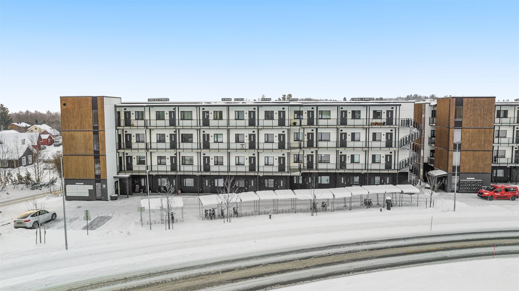 Fasade med inngangsparti, gjesteparkeringsplasser og sykkelparkering