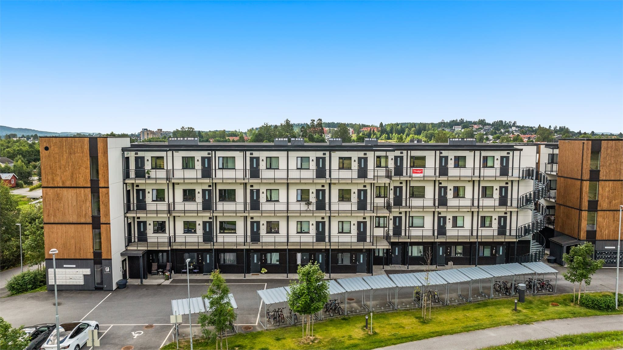 Fasade med inngangsparti, gjesteparkeringsplasser og sykkelparkering