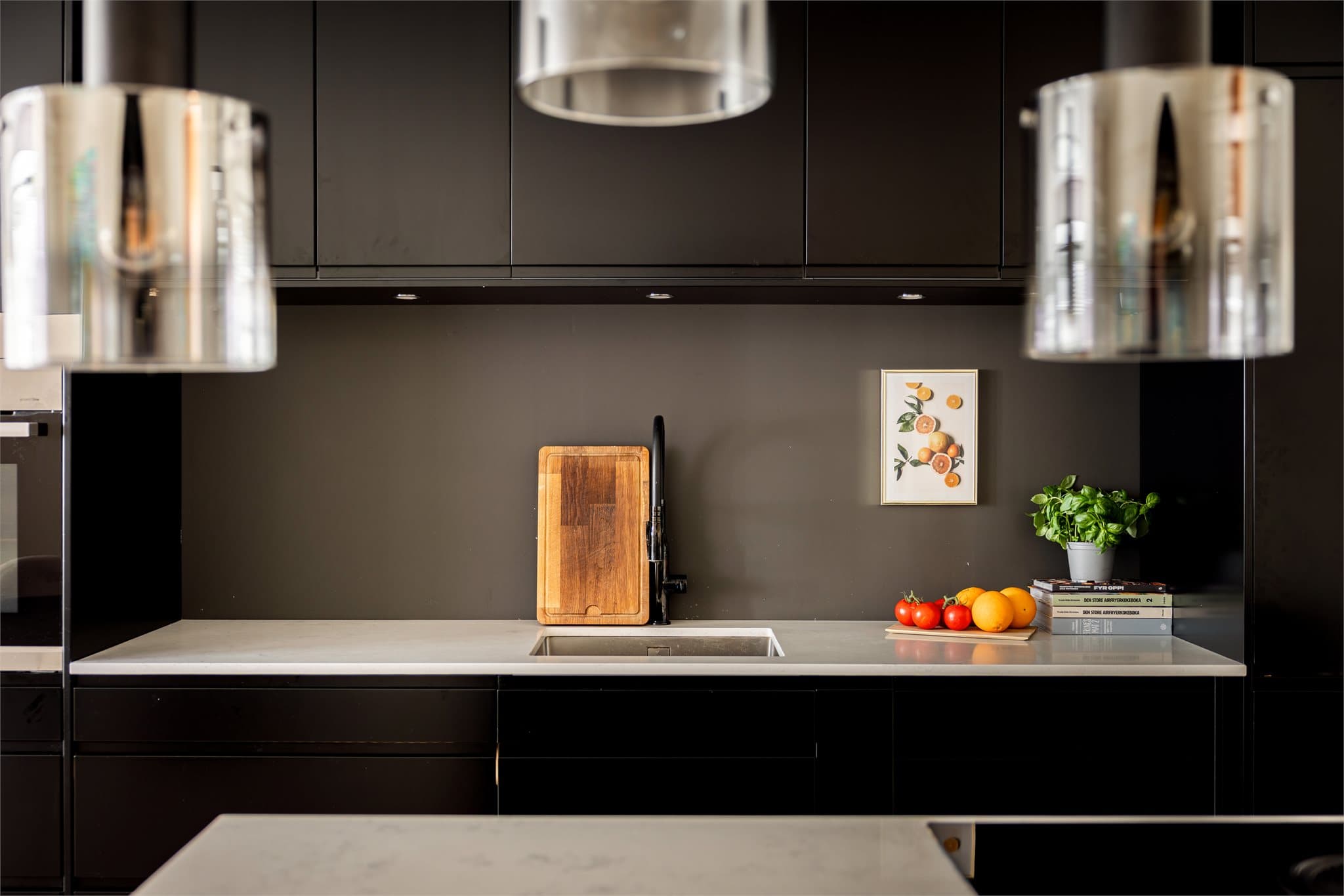 Steinkompositt benkeplate med underlimt kum i rustfritt stål gir et elegant uttrykk, og kjøkkenet er godt utrustet med integrerte hvitevarer: komfyr, platetopp med ventilator, micro, oppvaskmaskin og kjøl/frys.