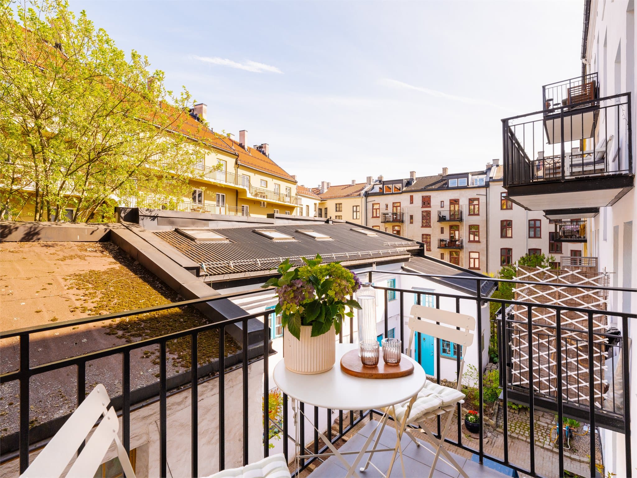 Her kan du nyte morgenkaffen ut mot en idyllisk bakgård som kan minne litt om Hellas med det hvite lille huset og de fargerike dørene/vinduene.