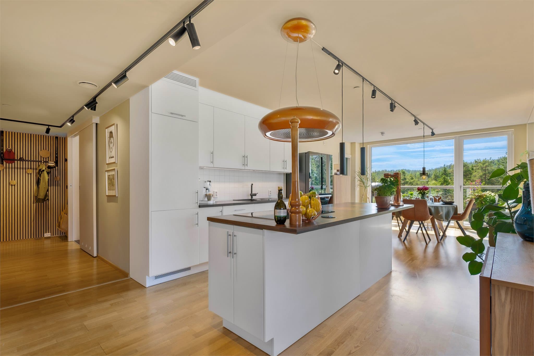 Fra entréen ledes man videre inn i boligen gjennom en lys og romslig gang med gjennomgående parkettgulv og en moderne materialpalett som går igjen i hele leiligheten.