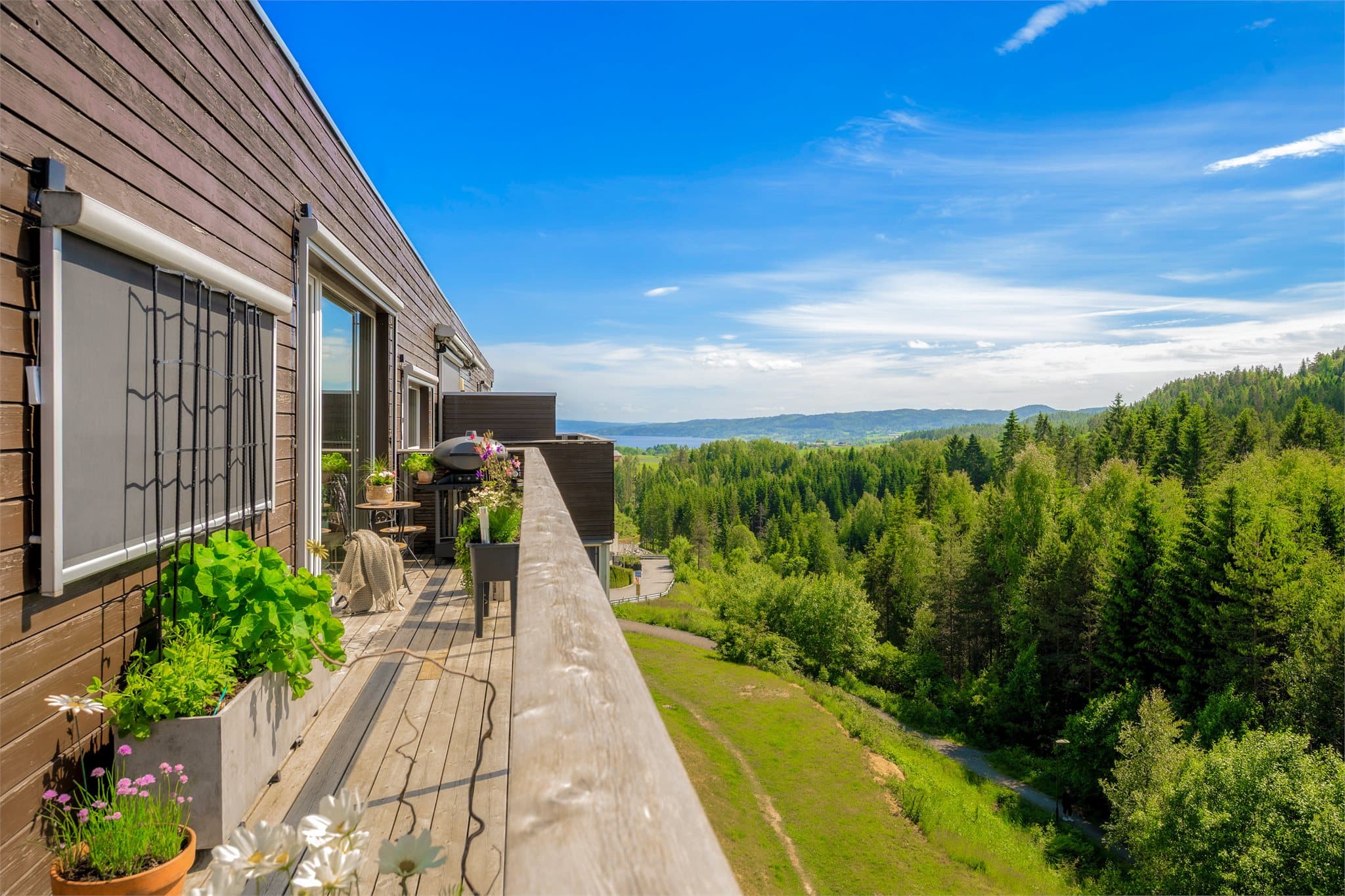 Den generøse, omkransende hjørneterrassen fungerer som en naturlig forlengelse av oppholdsrommene og byr på gode solforhold gjennom store deler av dagen. Terrassen har direkte adkomst via skyvedør fra stuen og balkongdør fra spisestuen.