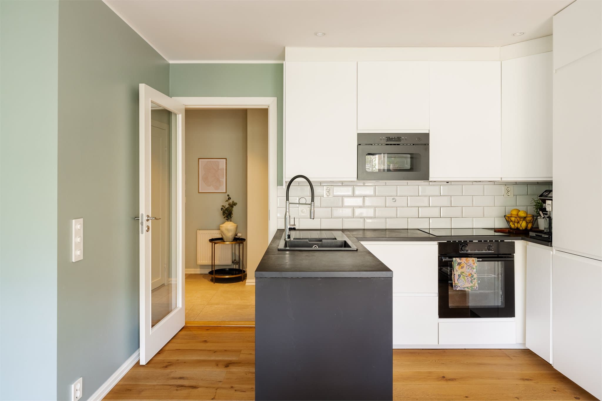 Et moderne og stilrent kjøkken med hvite fronter kombinert med elegante sorte detaljer - er virkelig et smykke i hovedsonen her.