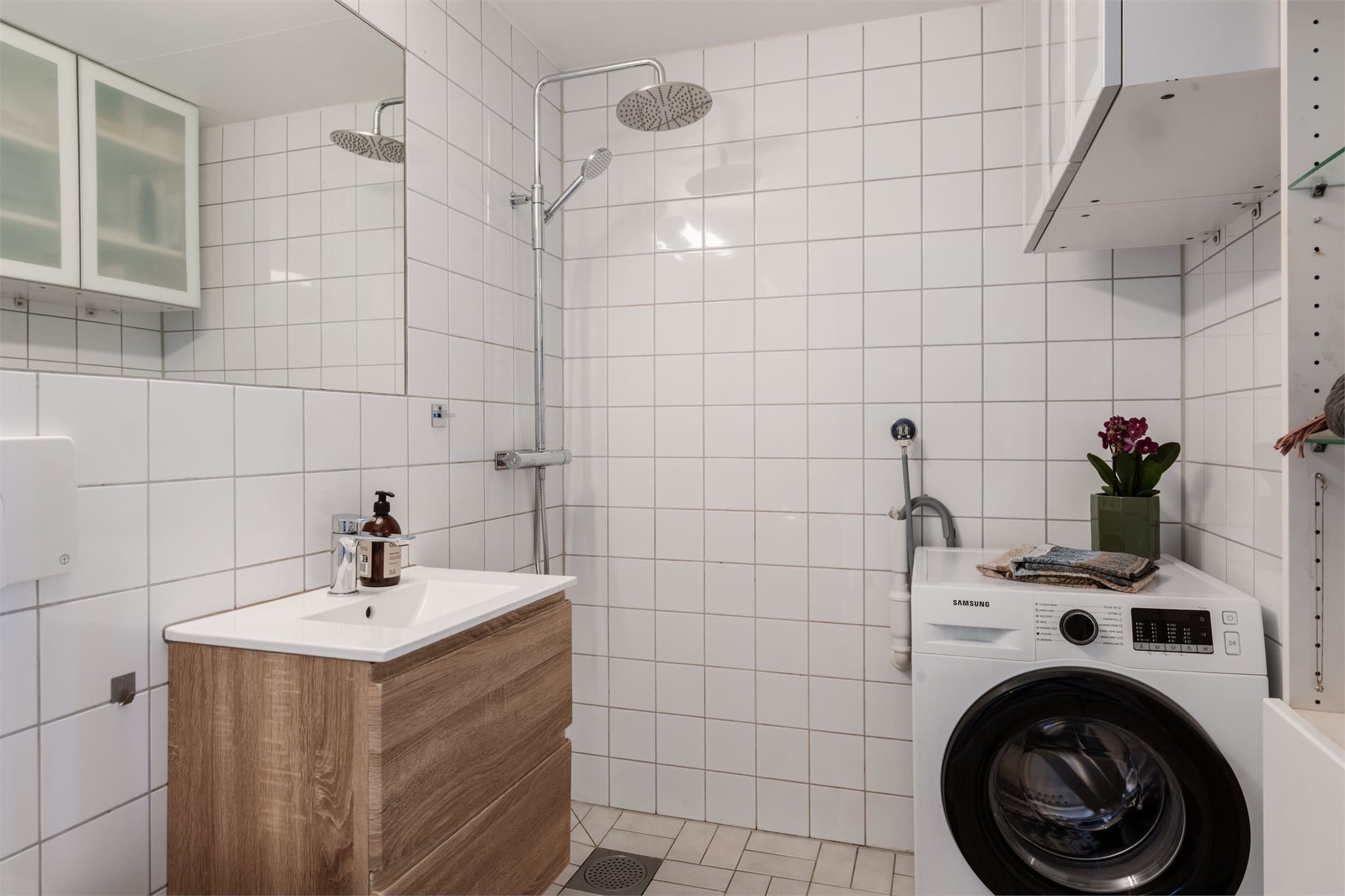 Badet er flislagt og praktisk innredet med opplegg for vaskemaskin.