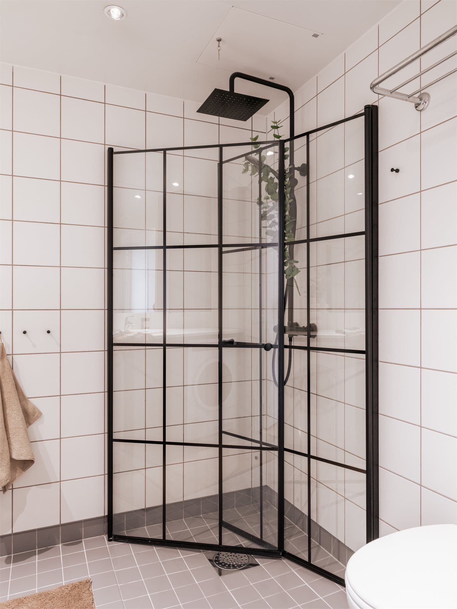 Romslig dusjnisje bak innfellbare dører i herdet glass. Takdusjen gir ekstra komfort i hverdagen.