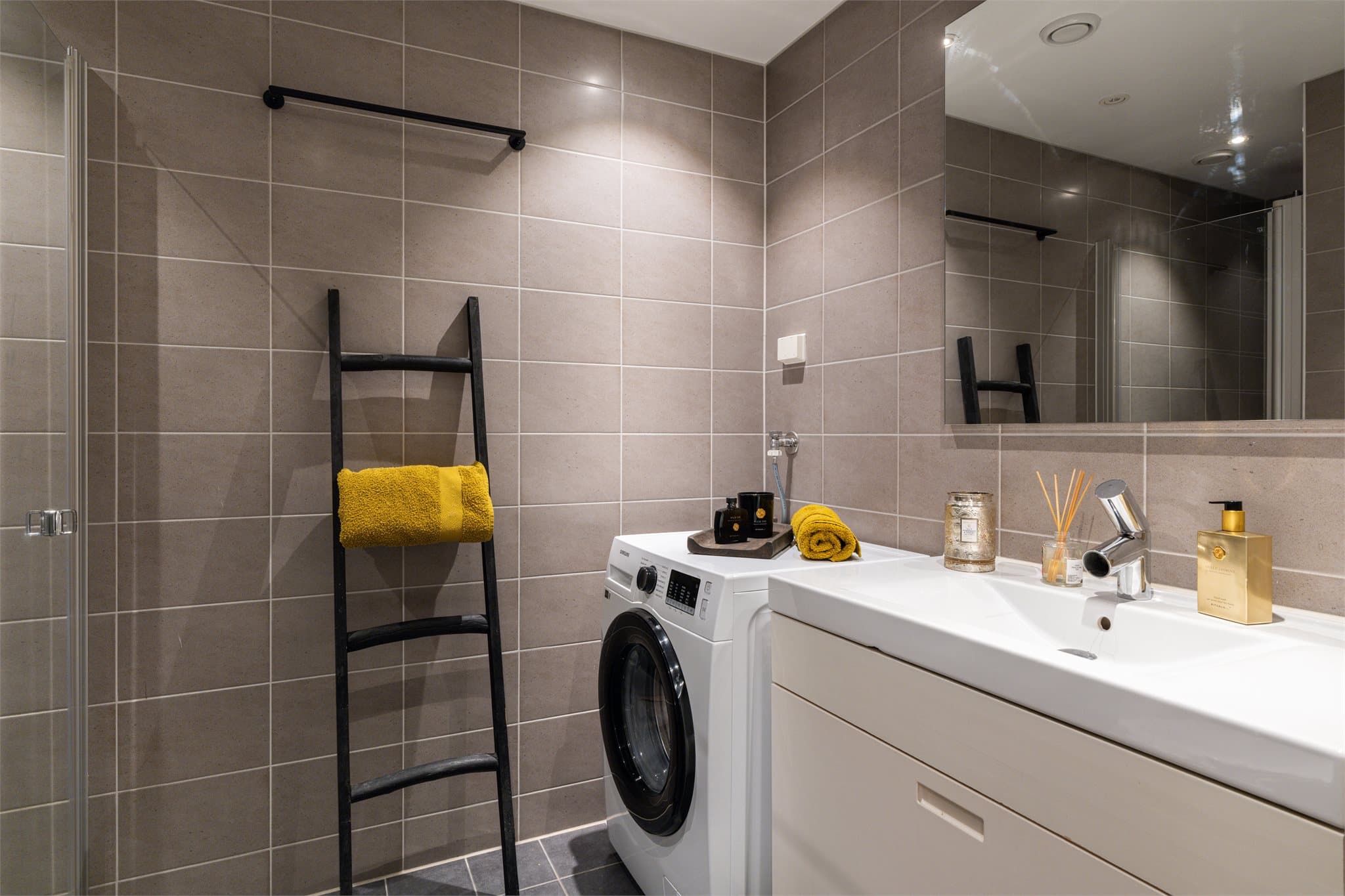 Baderommet er innredet med vegghengt klosett, servant, dusjhjørne med svingbar glassdør og speil.