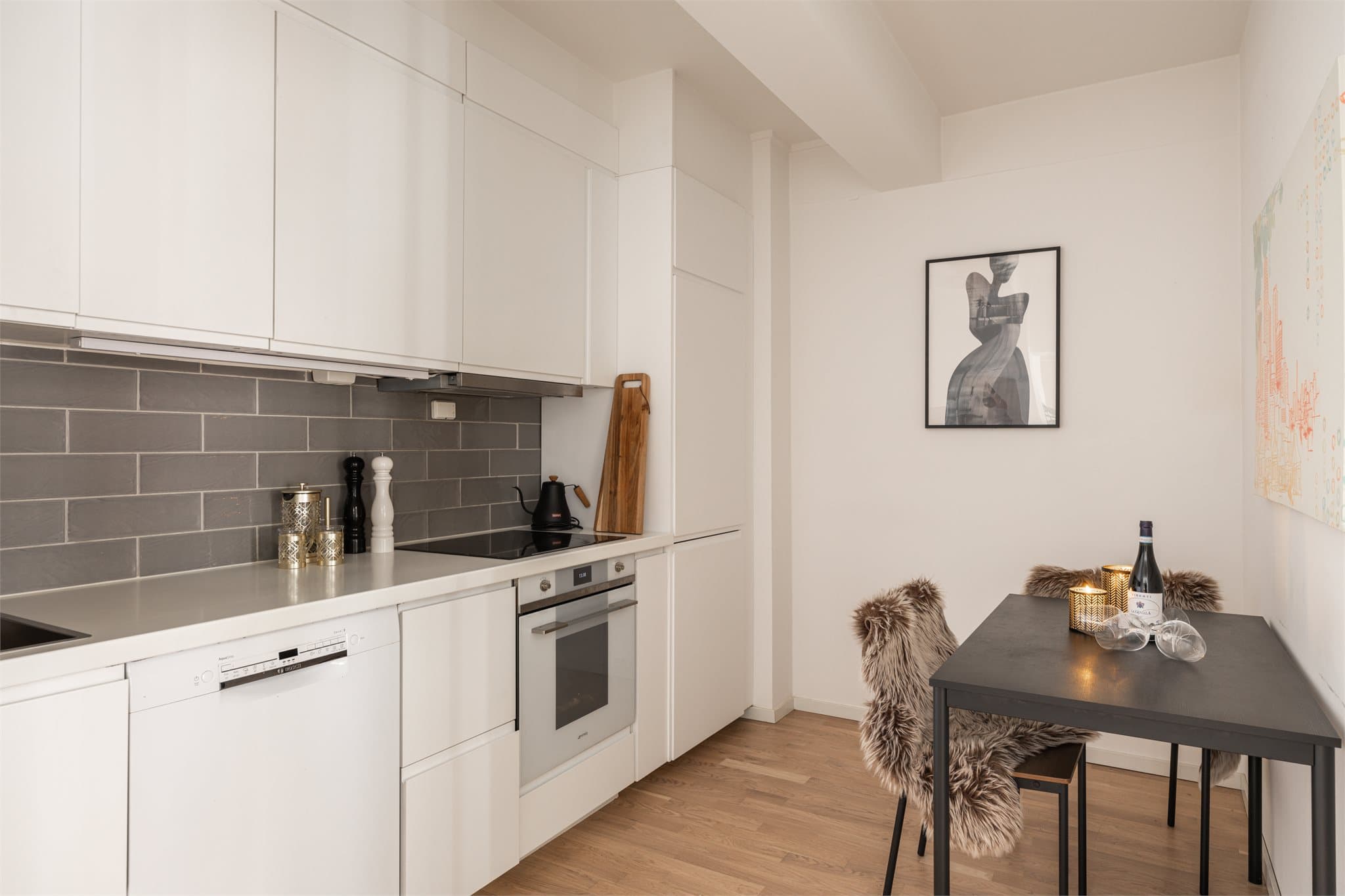 Kjøkkenet er innredet med glatte fronter, laminat benkeplate, nedfelt vask, samt fliser over kjøkkenbenk.