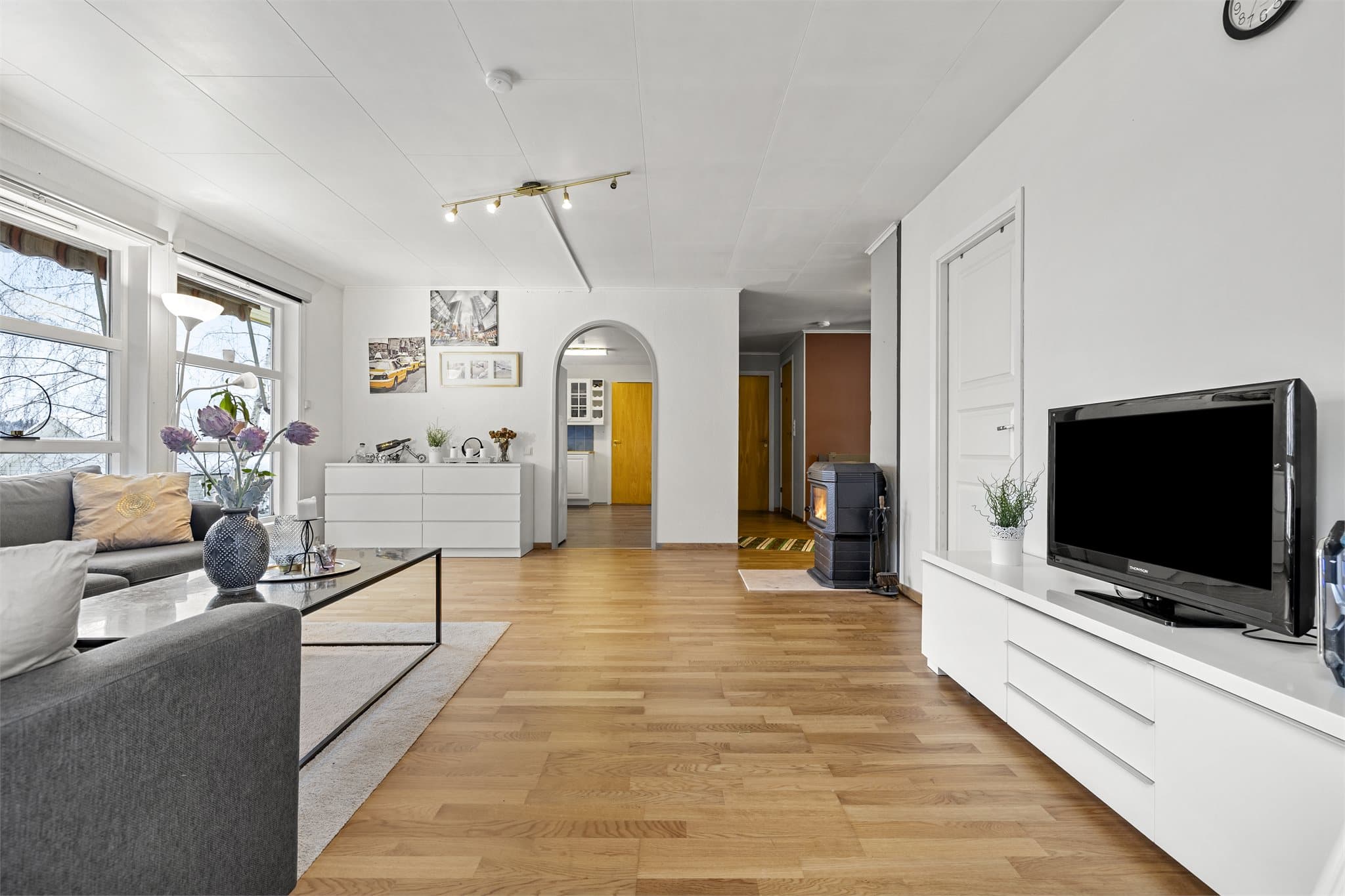 Lys og romslig stue med parkettgulv og store vindusflater som gir rikelig med naturlig lys.