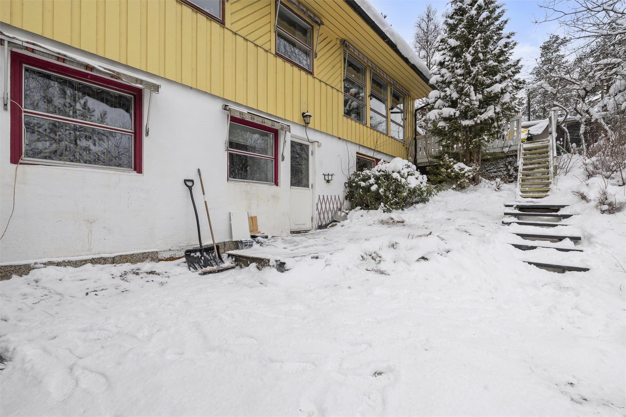 Fasade med kjellervinduer og adkomst til underetasjen.