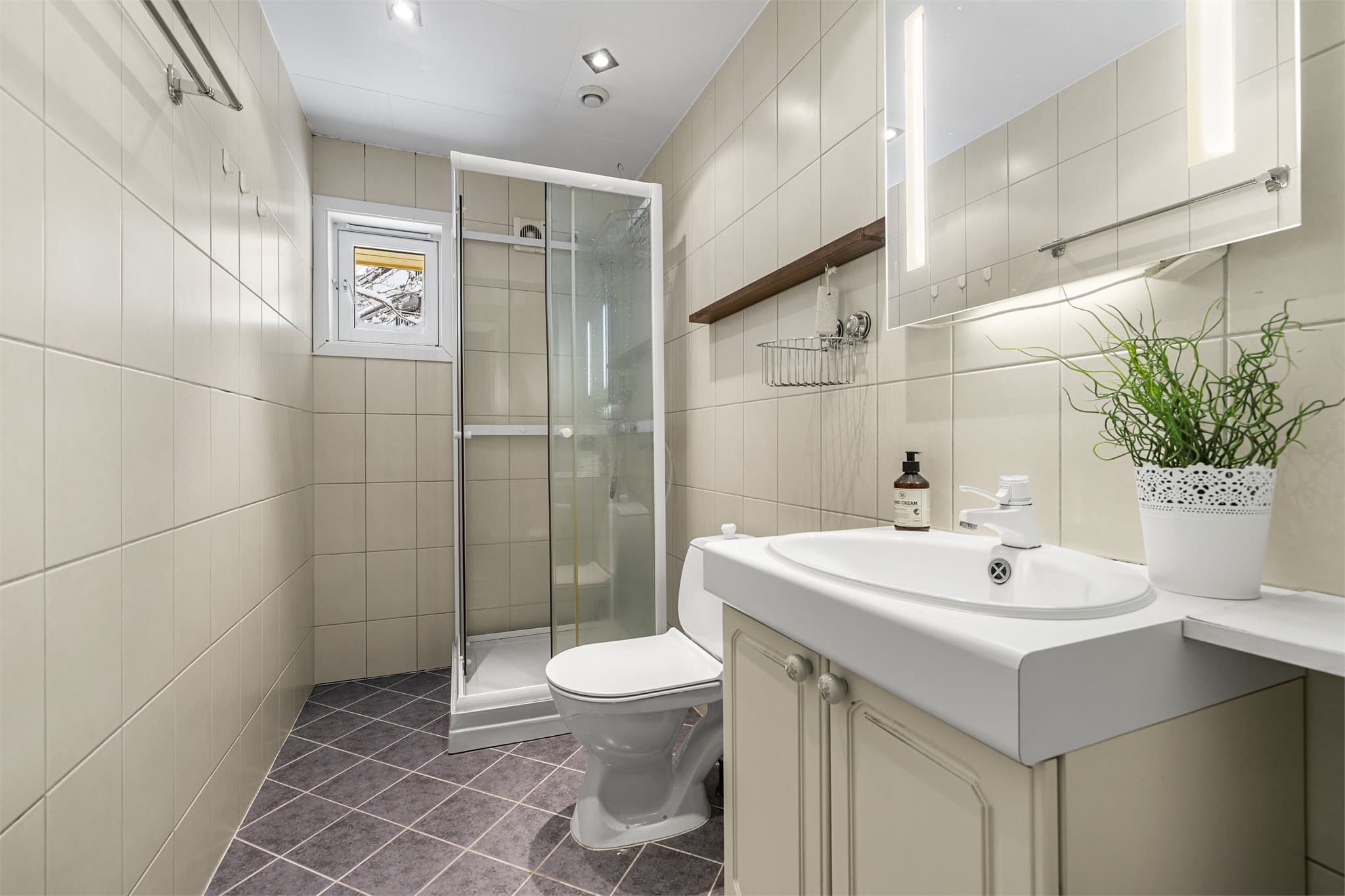 Bad med flislagt gulv og vegger, dusjløsning og varmekabler i gulv.