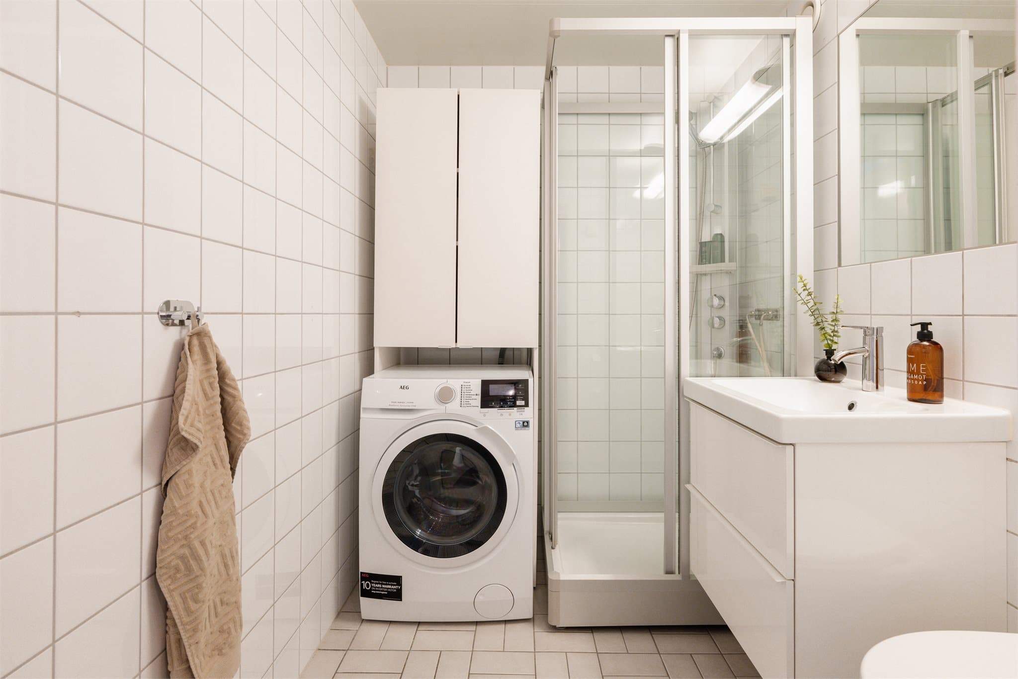 Flislagt baderom med varme i gulvet og praktisk opplegg for vaskemaskin.