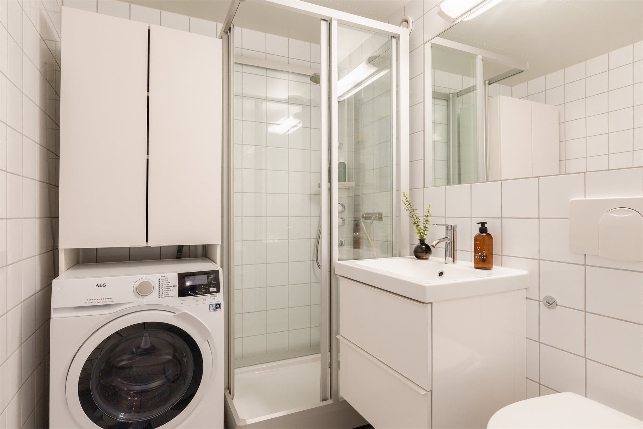 Rommet er utstyrt med servantskap, speil og dusjkabinett med skyvedør.