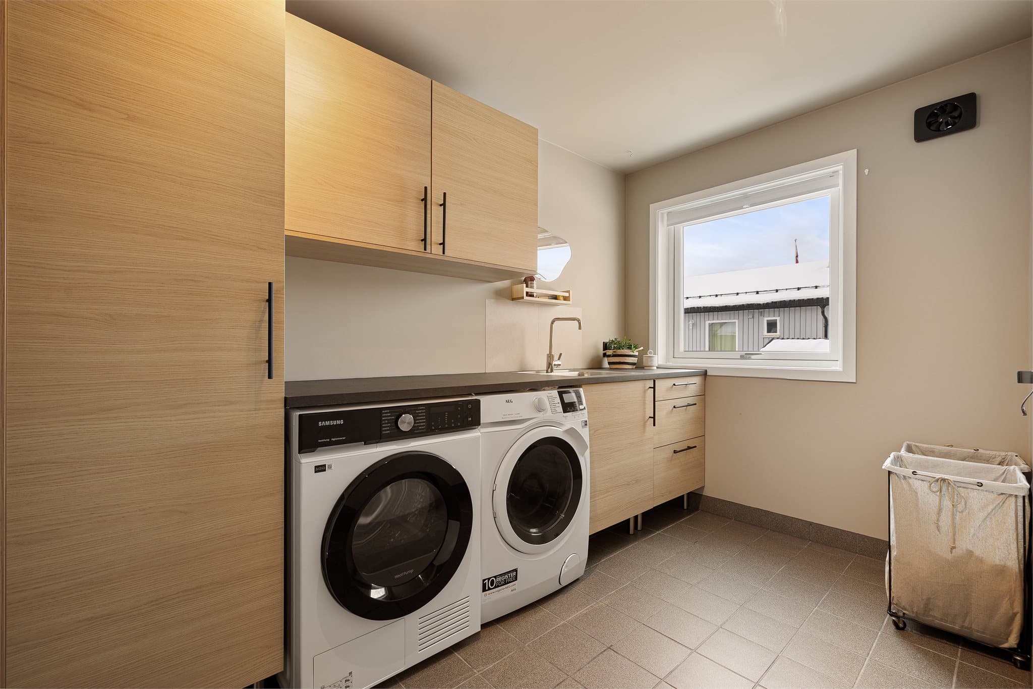 Praktisk vaskerom med god benkeplass og rikelig med lagringsplass i skap og skuffer.