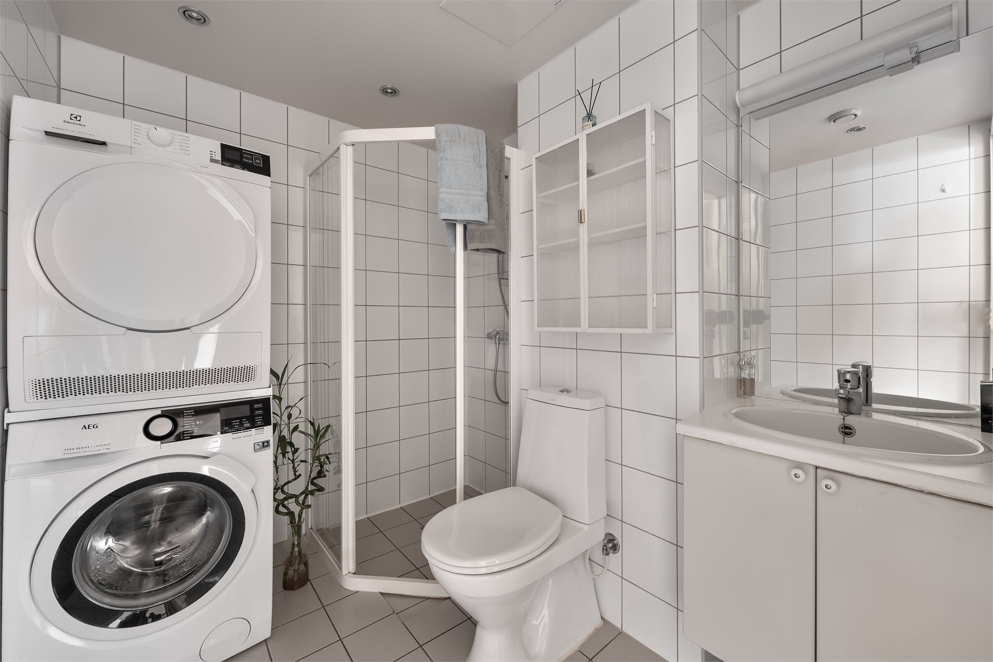 Helfliset baderom med gulvvarme, downlights, gulvstående toalett, servant og dusjhjørne.