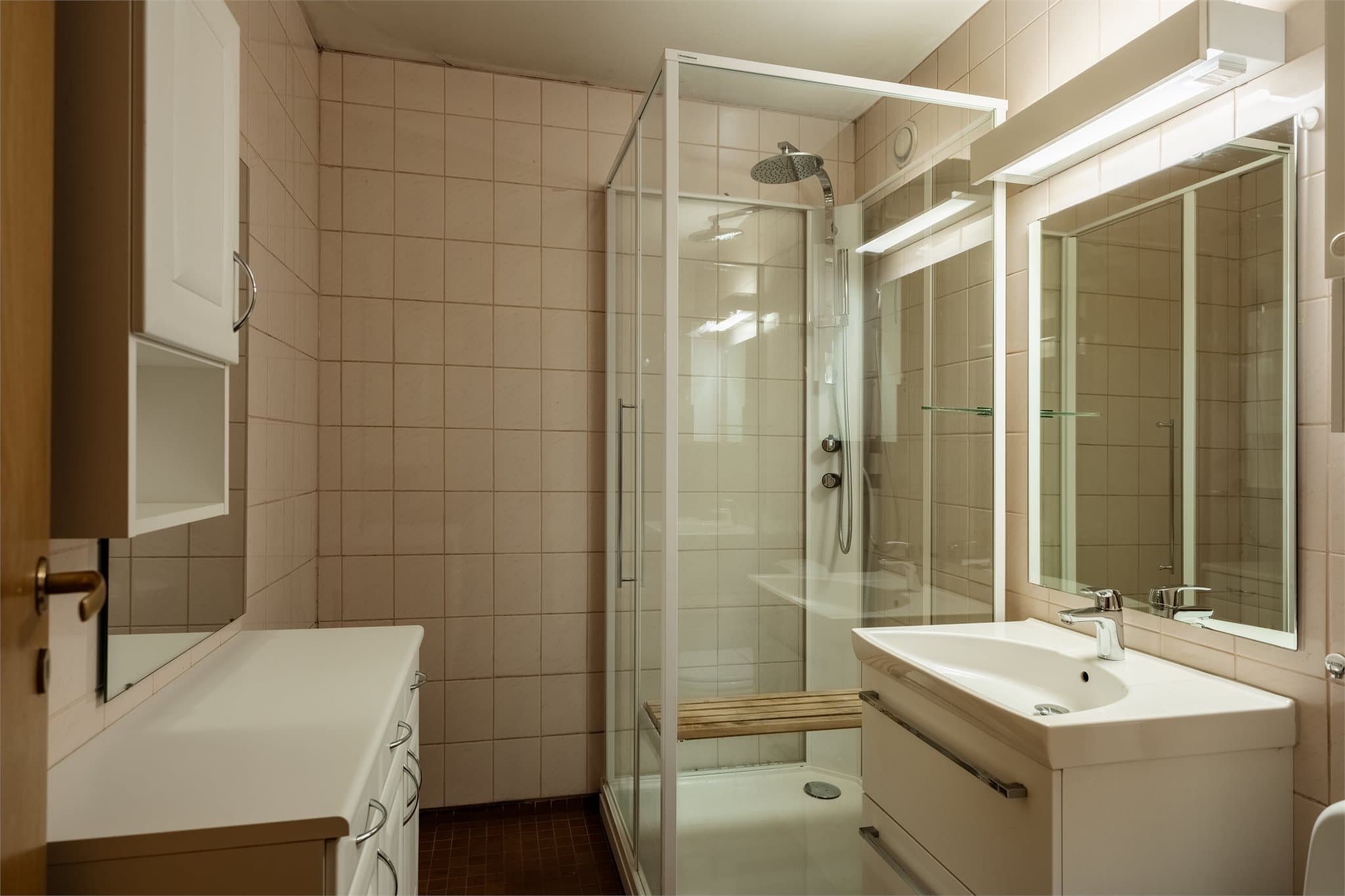Badet er utstyrt med dusjkabinett, servant med skuffeinnredning og gulvmontert klosett