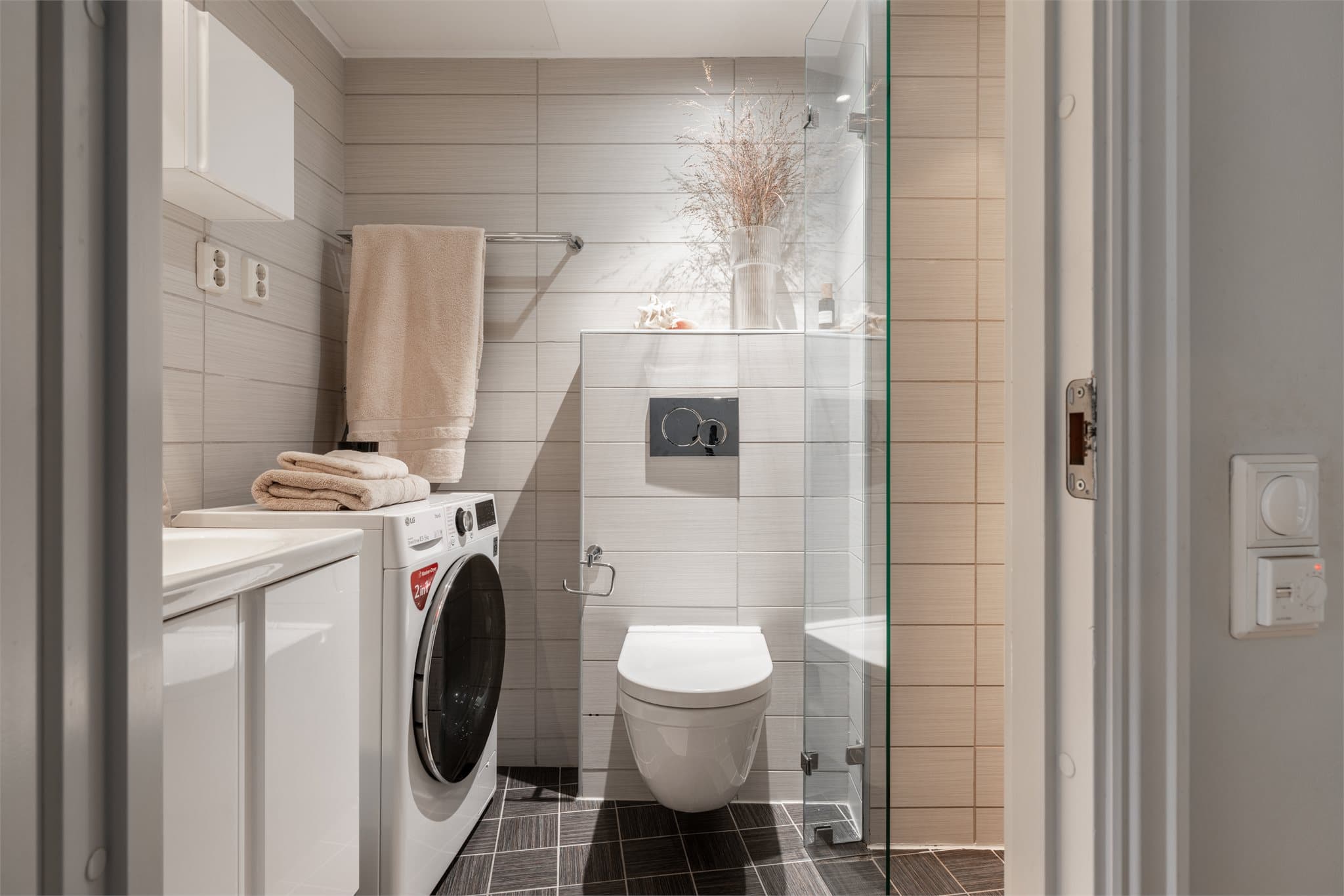 Moderne, flislagt bad med elektrisk gulvvarme, vegghengt toalett og opplegg for vaskemaskin.