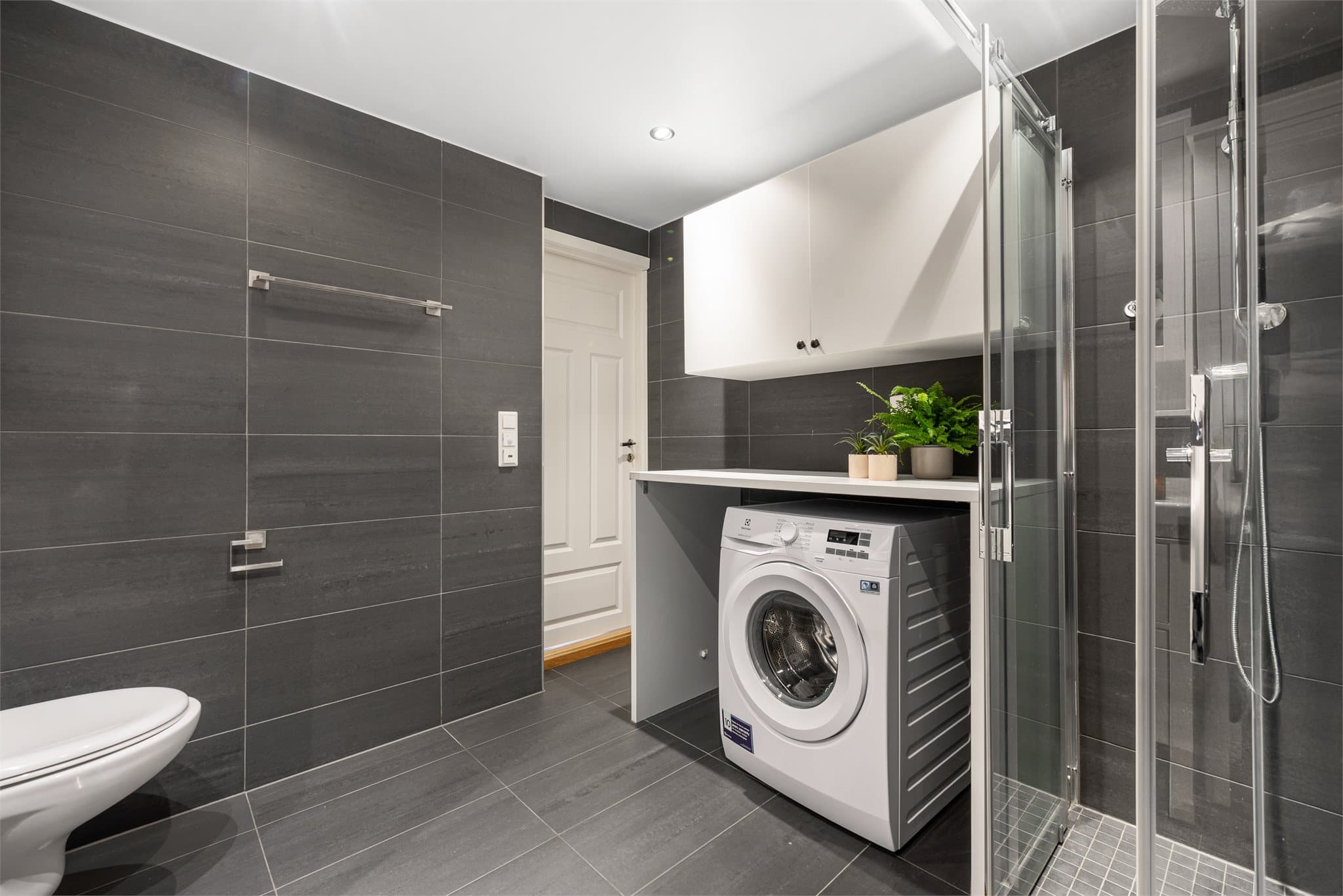 Baderommet er praktisk innredet med plass til både vaskemaskin og tørketrommel hvis ønskelig under benkeplate som gir gode arbeidsflater når klesvasken skal brettes og sorteres.