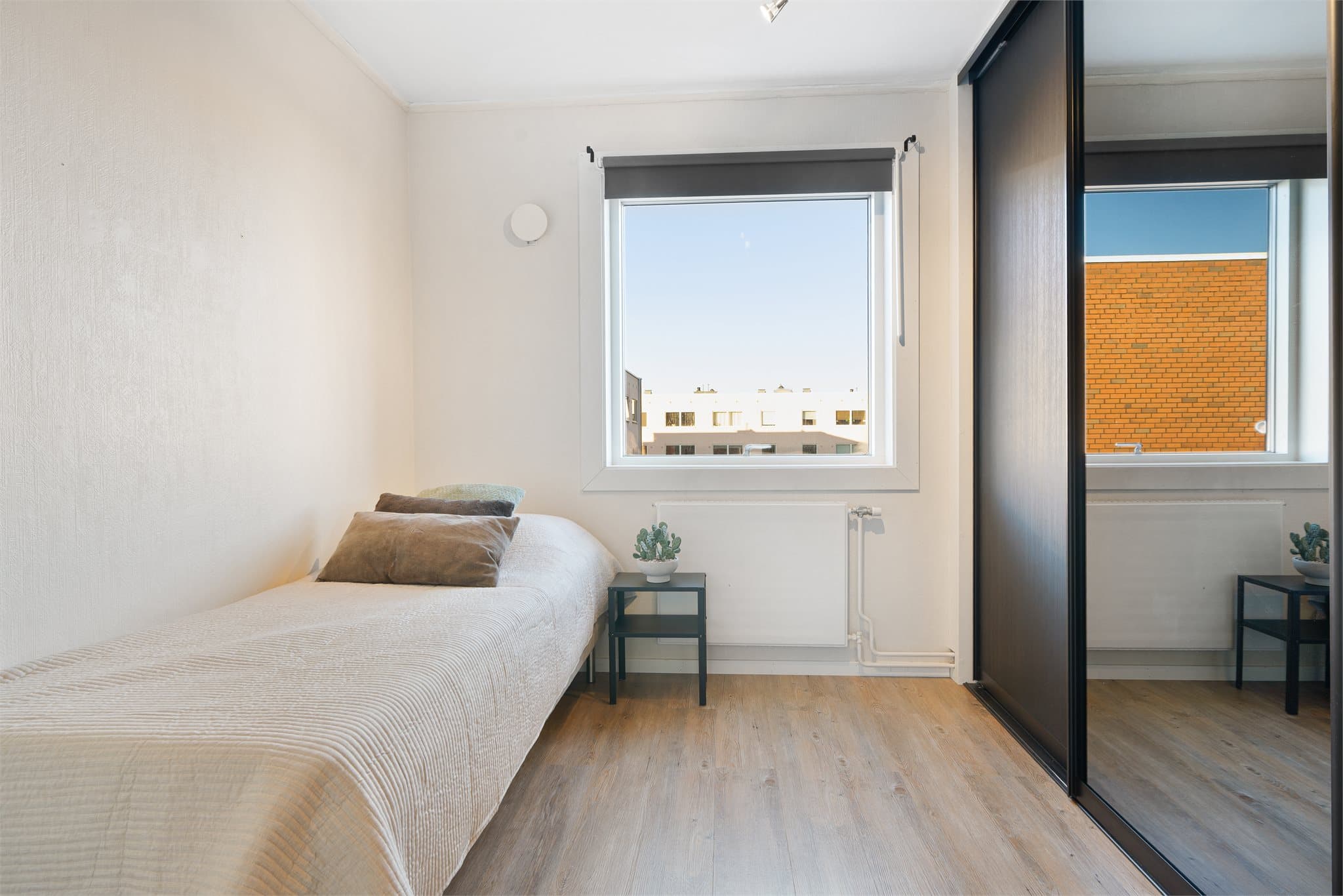 Soverom 2 har en romslig skyvedørsgarderobe i moderne sort og praktiske speilfronter.