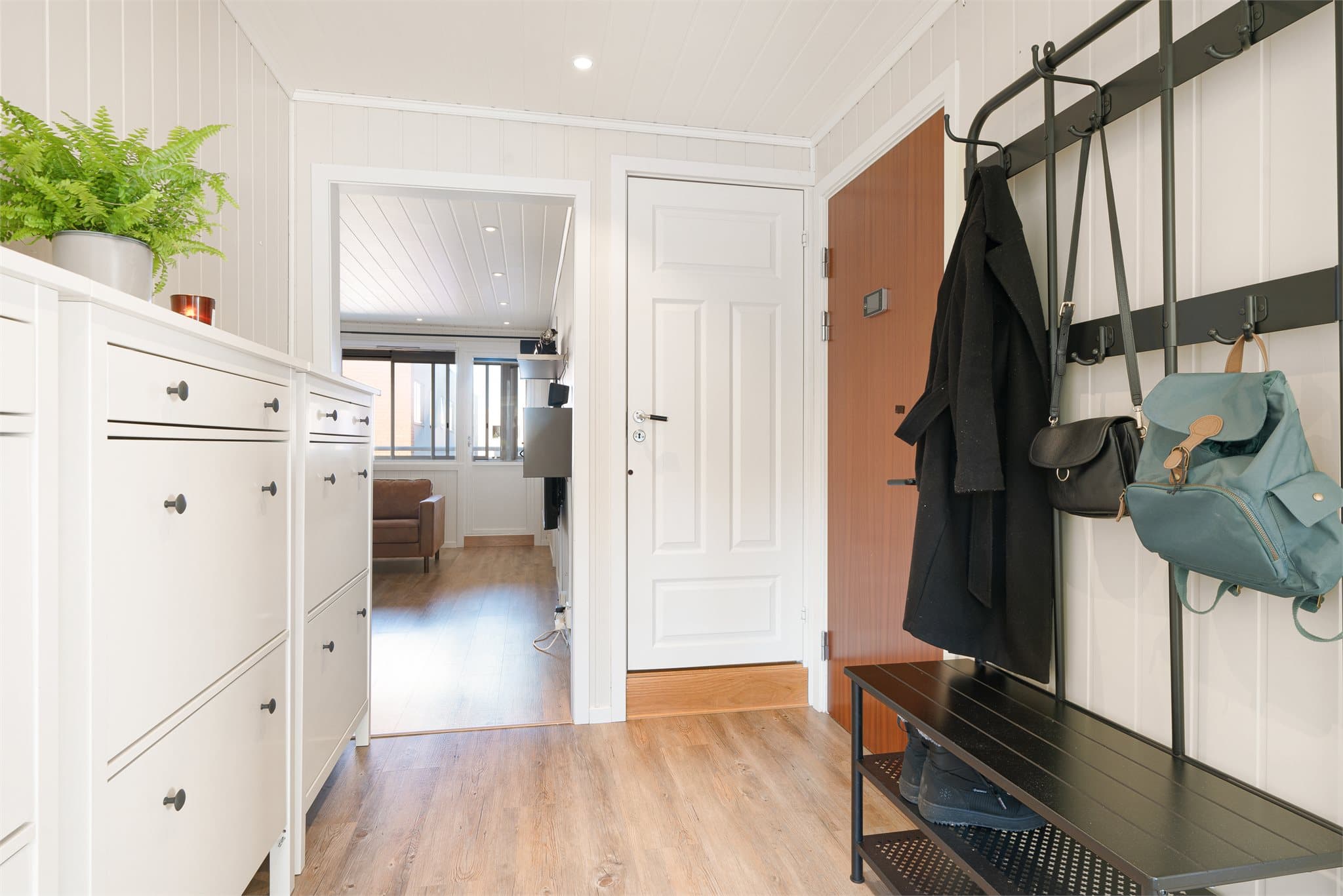 Velkommen inn! Lys entré med lysmalte panelplater og rikelig med oppbevaring for sko og yttertøy. Det er gjennomgående downlightsbelysning i himling i leiligheten.