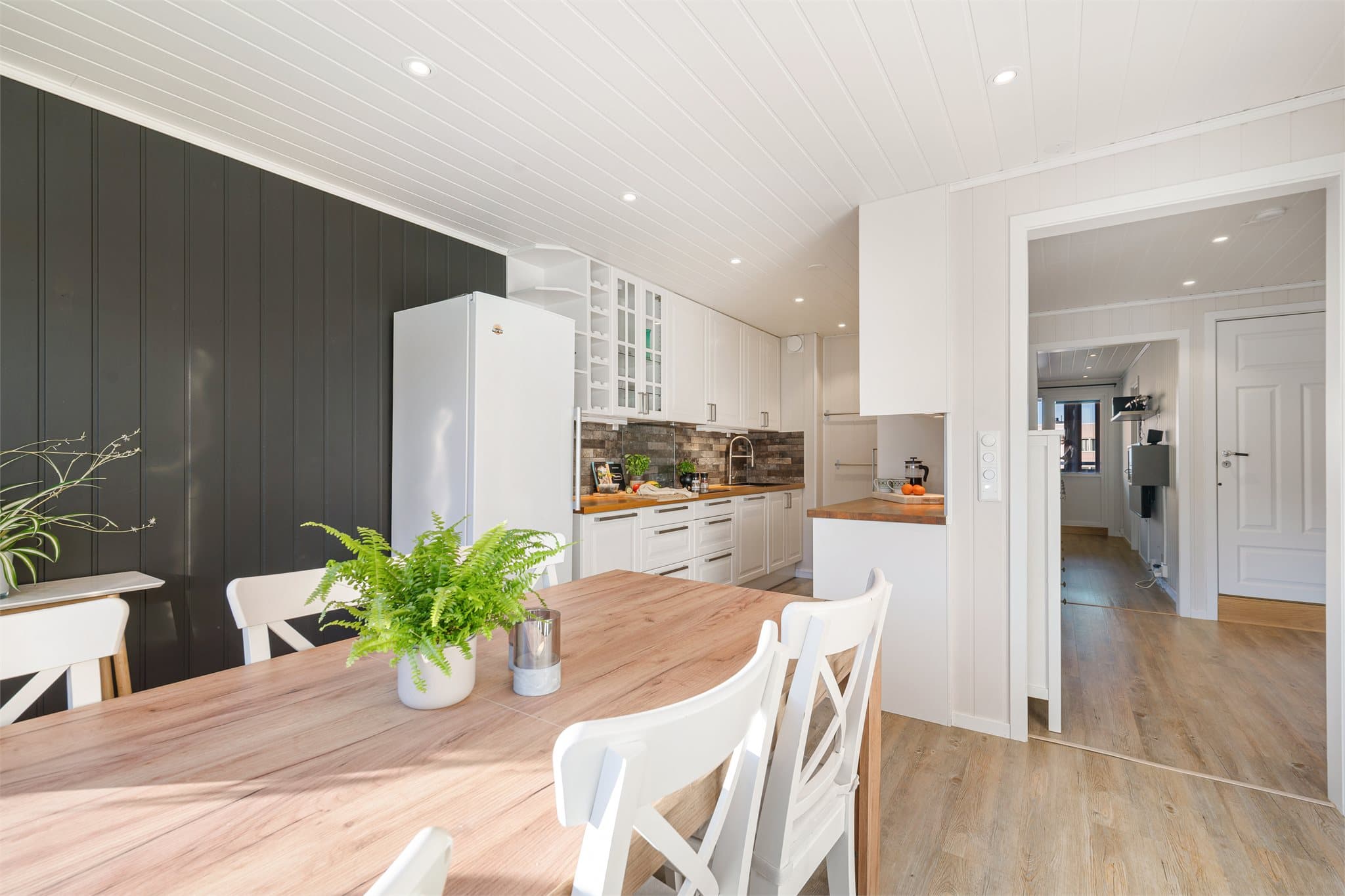 Lekkert og innbydende kjøkken i eget rom, med stilren Ikea-innredning i hvite, profilerte fronter som gir et klassisk og elegant uttrykk.