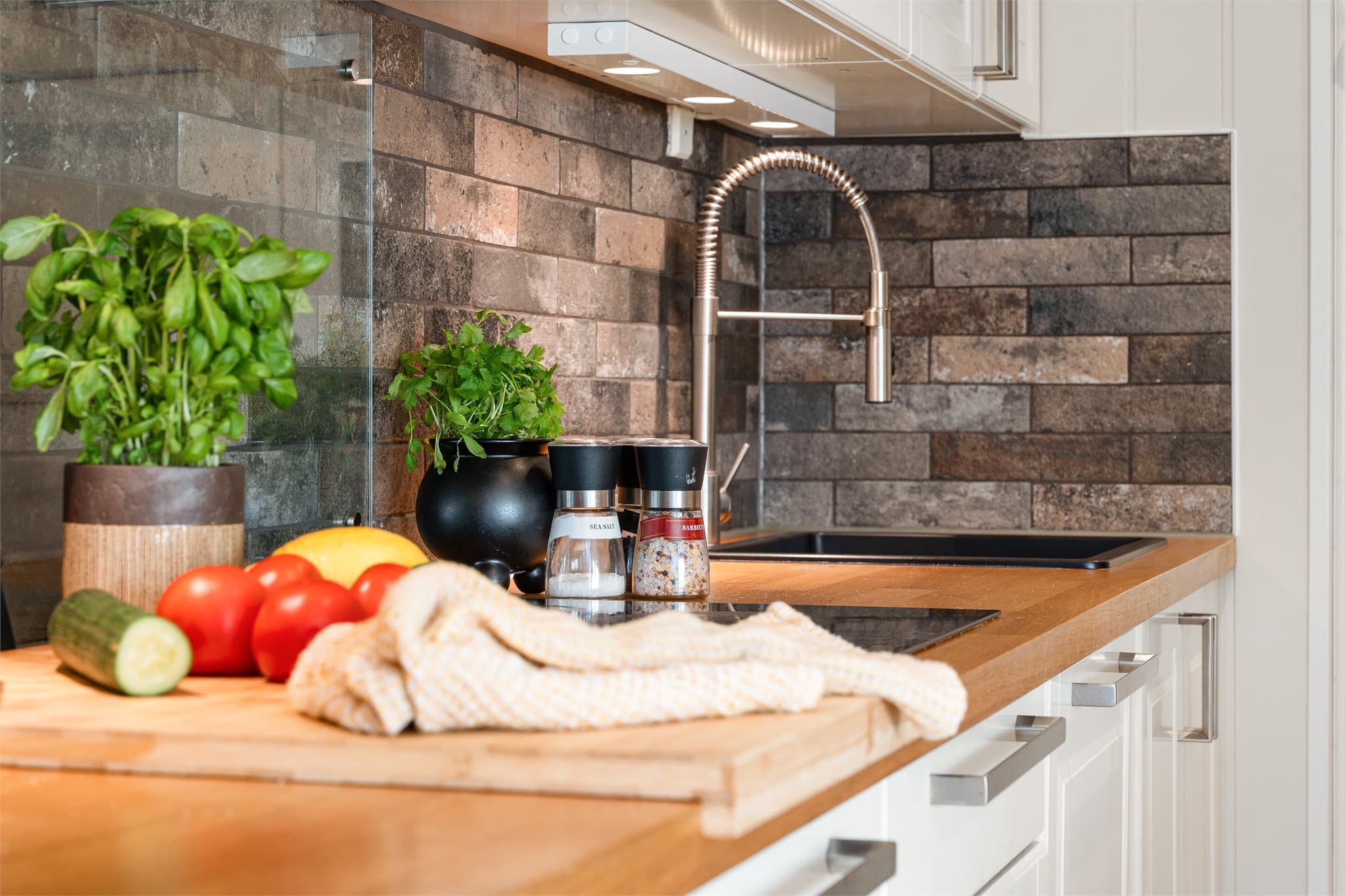 Den solide heltre benkeplaten gir rommet varme og et eksklusivt preg, og står i flott kontrast til den moderne, sorte komposittvasken med tilhørende sort armatur.