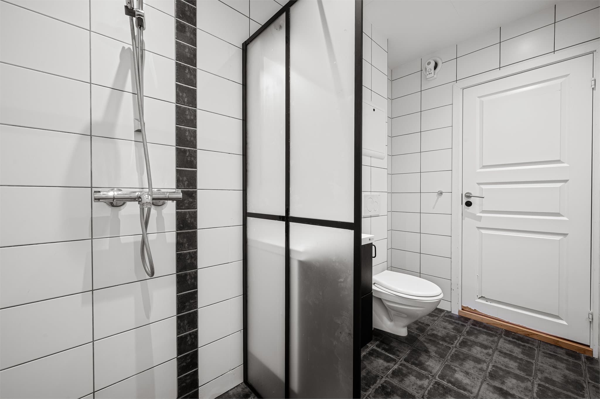 - Badet er innredet med vegghengt toalett, heldekkende servant og dusjvegg. Merk sorte detaljer -