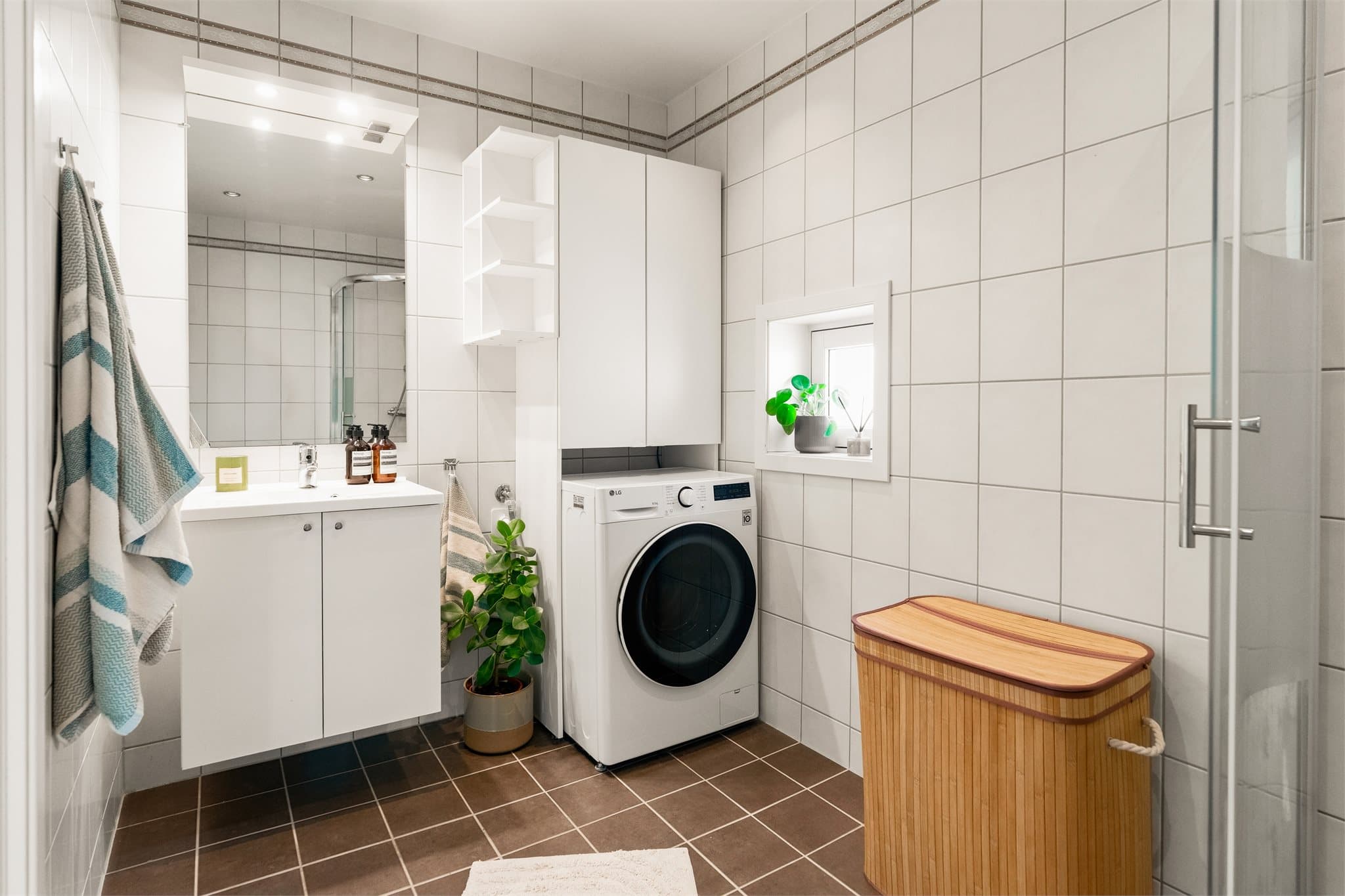 Badet er innredet med hvite veggfliser, mørke gulvfliser, downlights og gulvvarme.