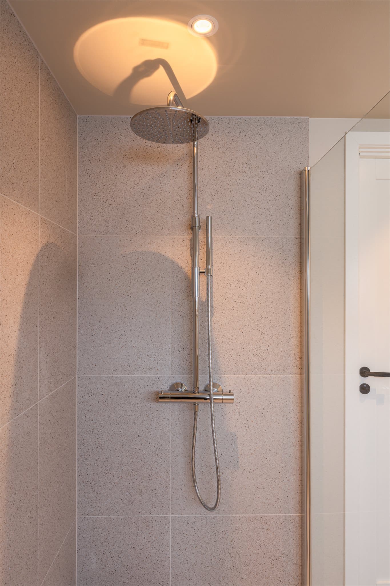 Dusjhjørnet er helfliset med regnfallsdusj, hånddusj og innfellbare glassdører.