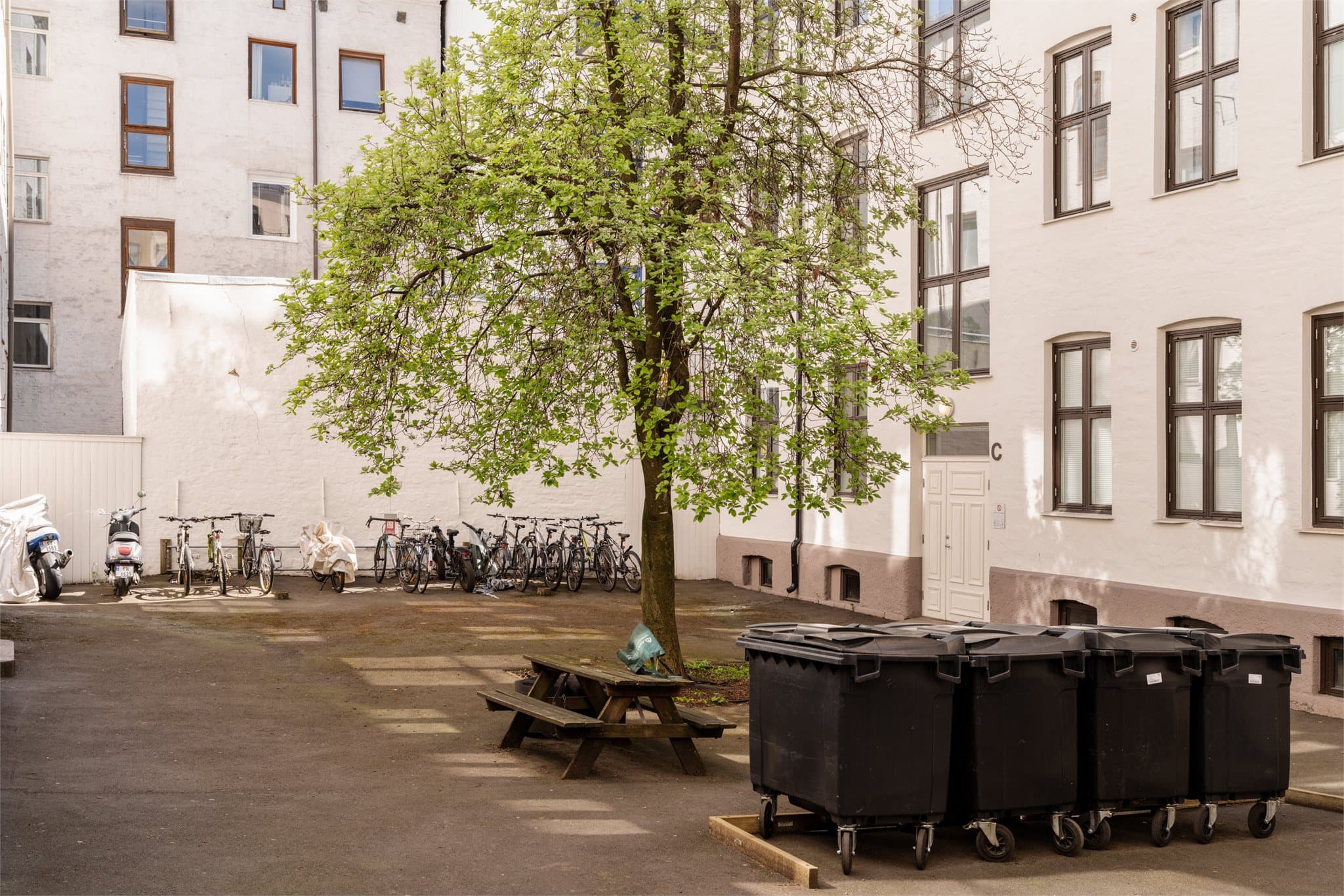 Skjermet bakgård med sittegrupper og sykkelparkering.