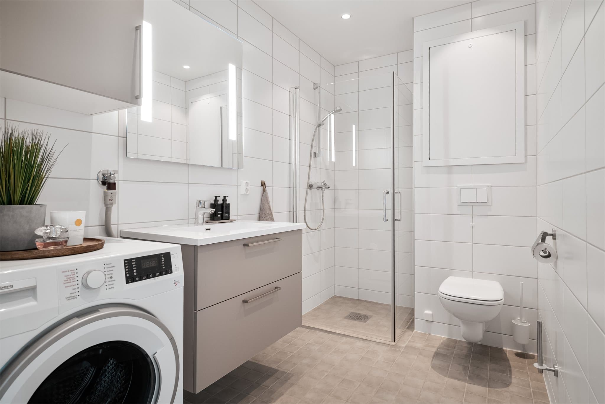 Moderne og stilrent bad med downlights i himling, HTH baderomsinnredning og opplegg for vaskemaskin.