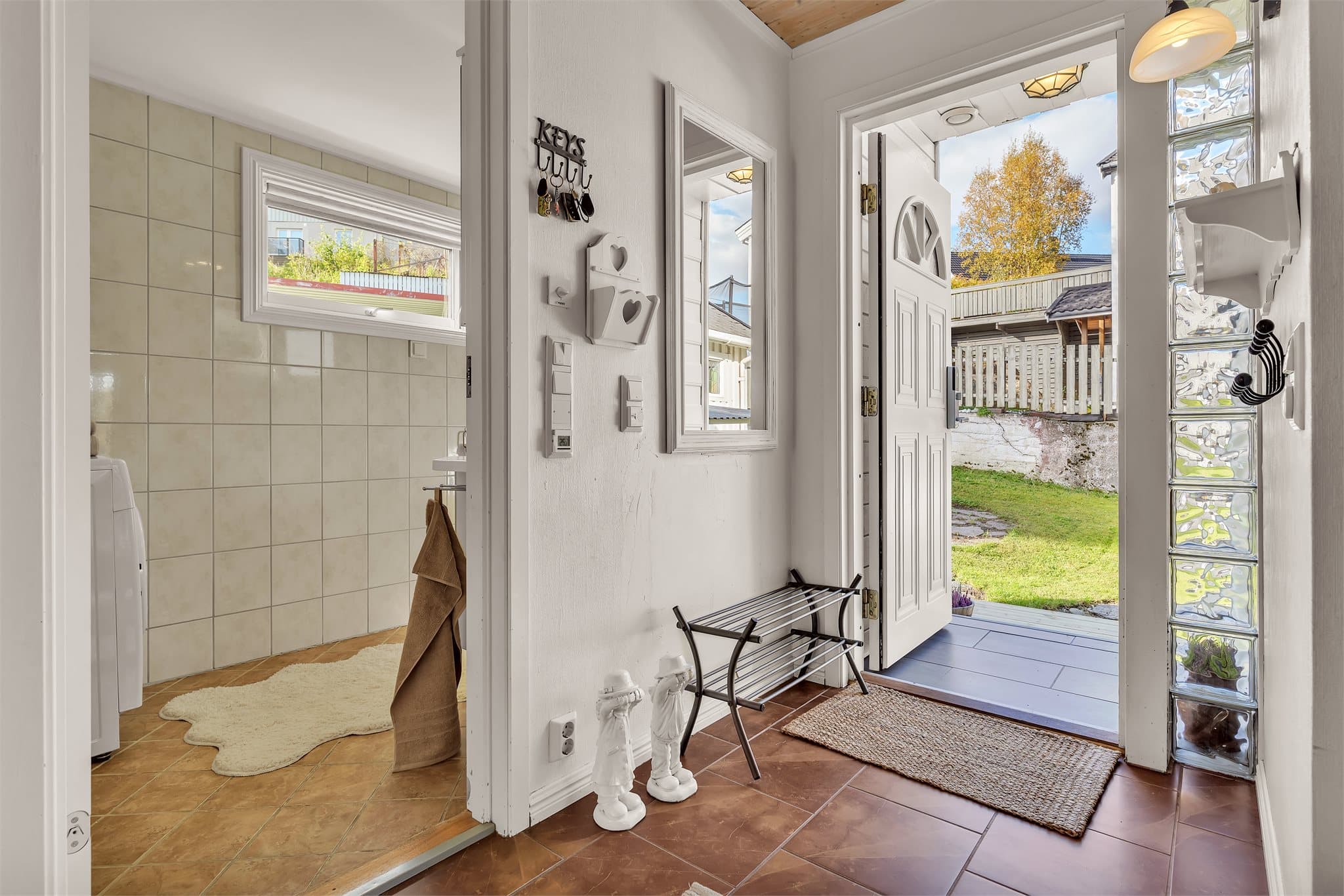 Malt ytterdør med glassfelt og smartlås, plassert like ved baderomsinngangen.