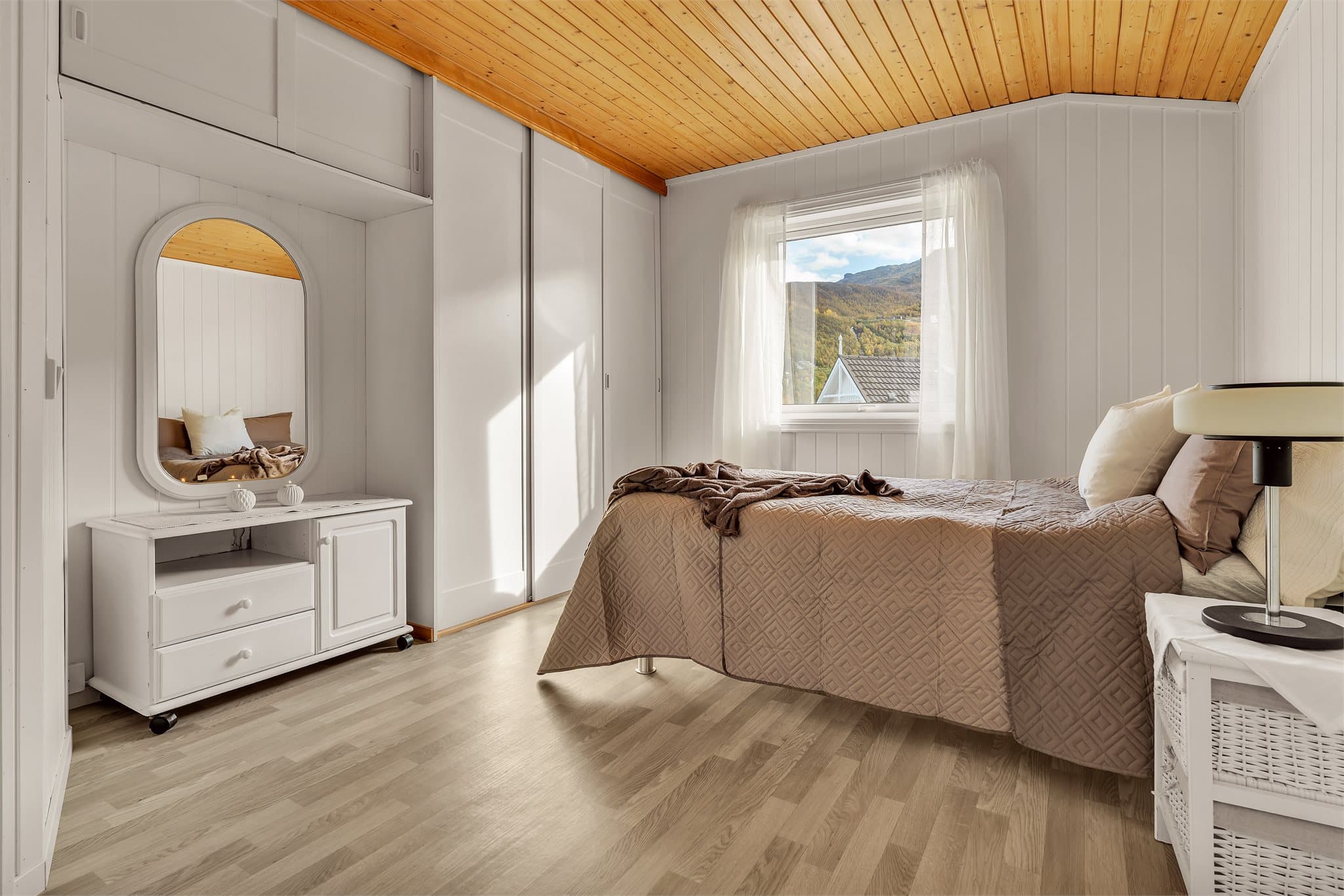 Rommet er utstyrt med skyvedørsgarderobe og tilhørende overskap for god oppbevaring.