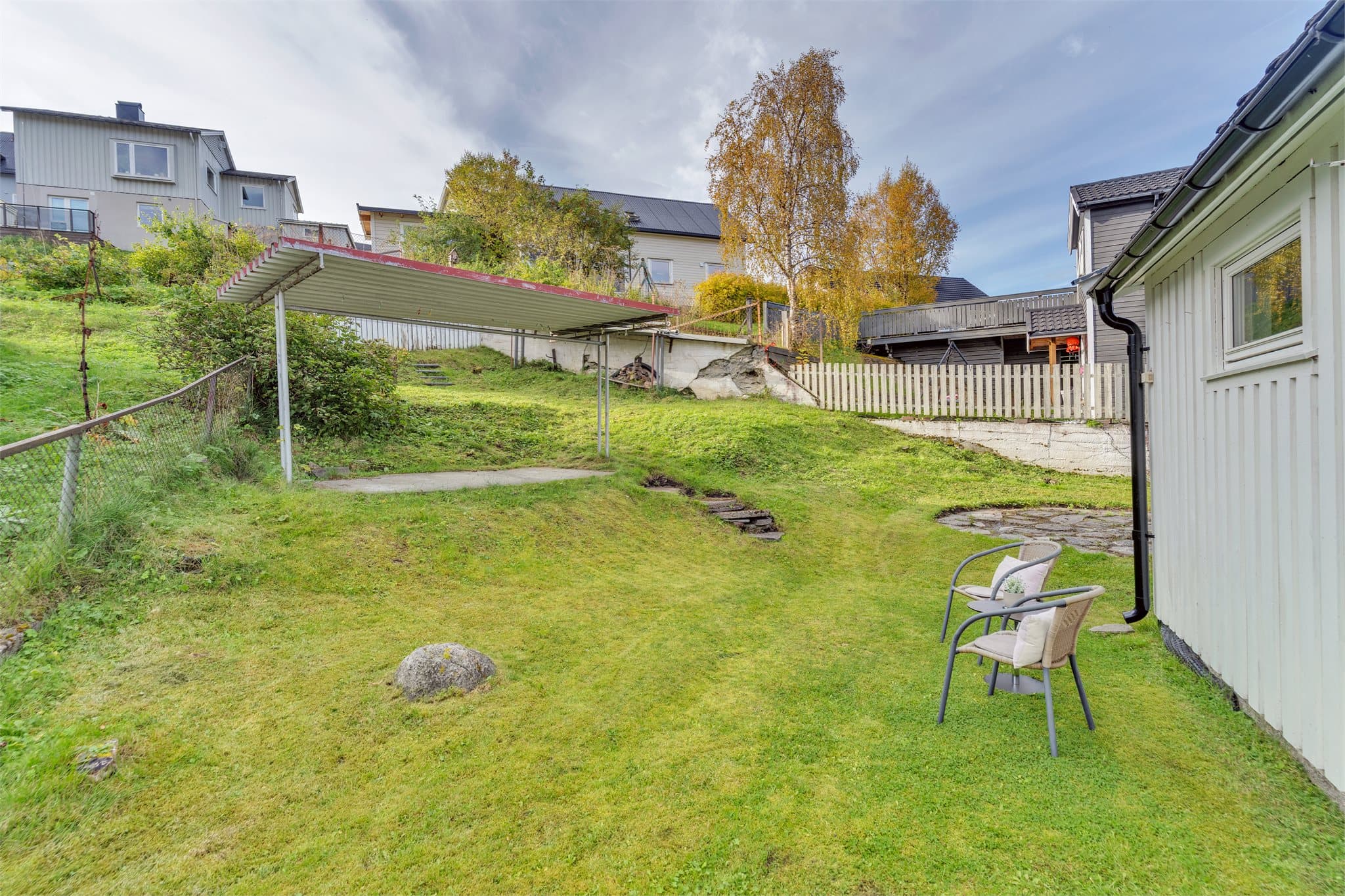 Skrånende tomt opparbeidet med plen, velegnet for lek og utendørsaktiviteter.
