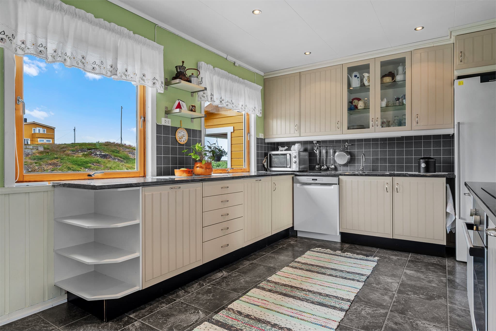 Store vindusflater som slipper inn rikelig med naturlig lys og gir kjøkkenet en lys og luftig atmosfære.
