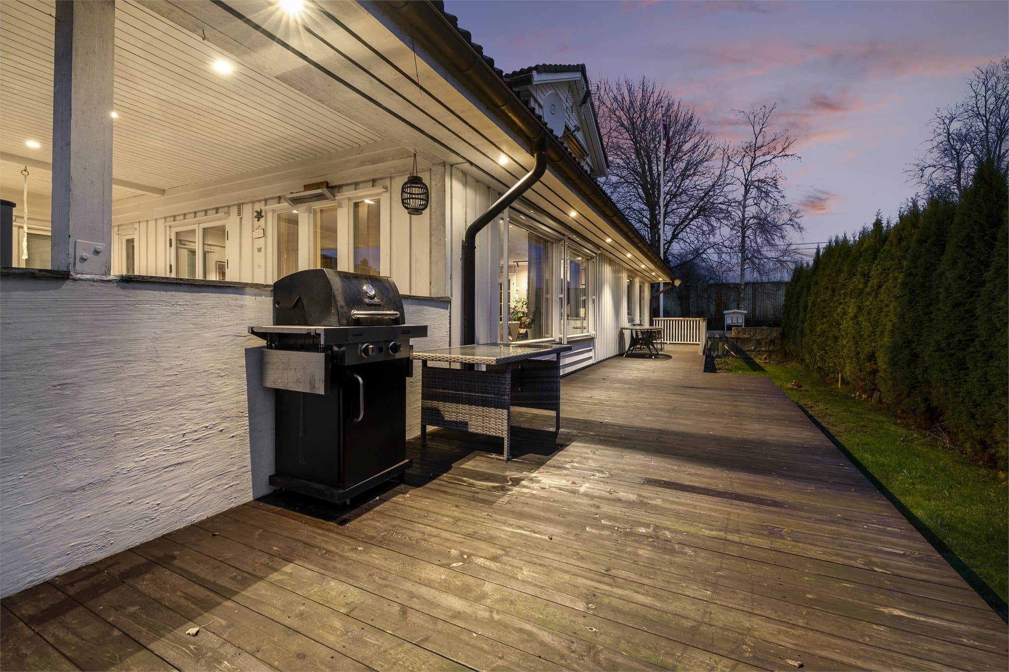 Stor og solrik terrasse som strekker seg rundt to av husets fire vegger.