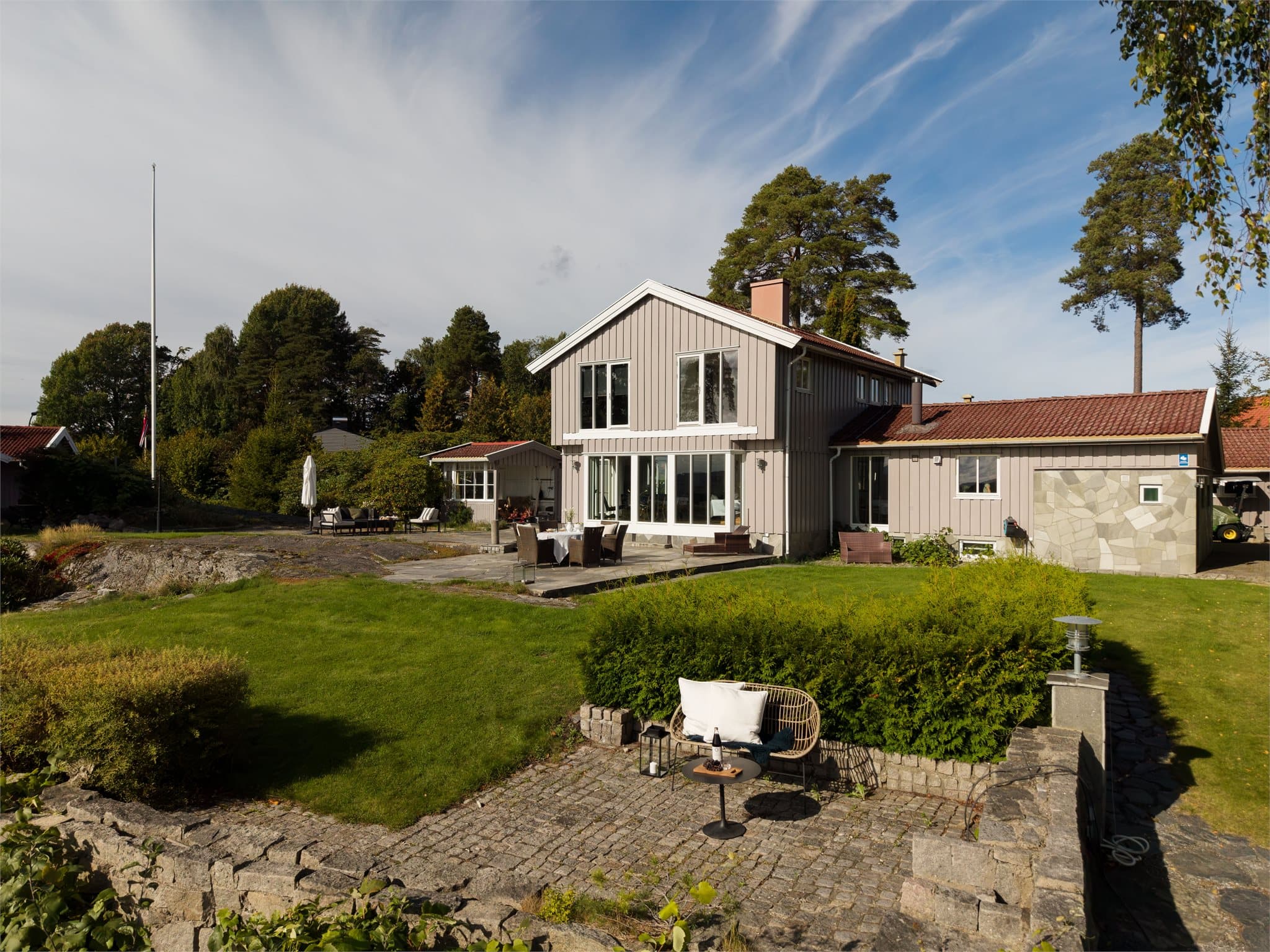 Den brosteinsbelagte uteplassen ligger i hagens nedre nivå.