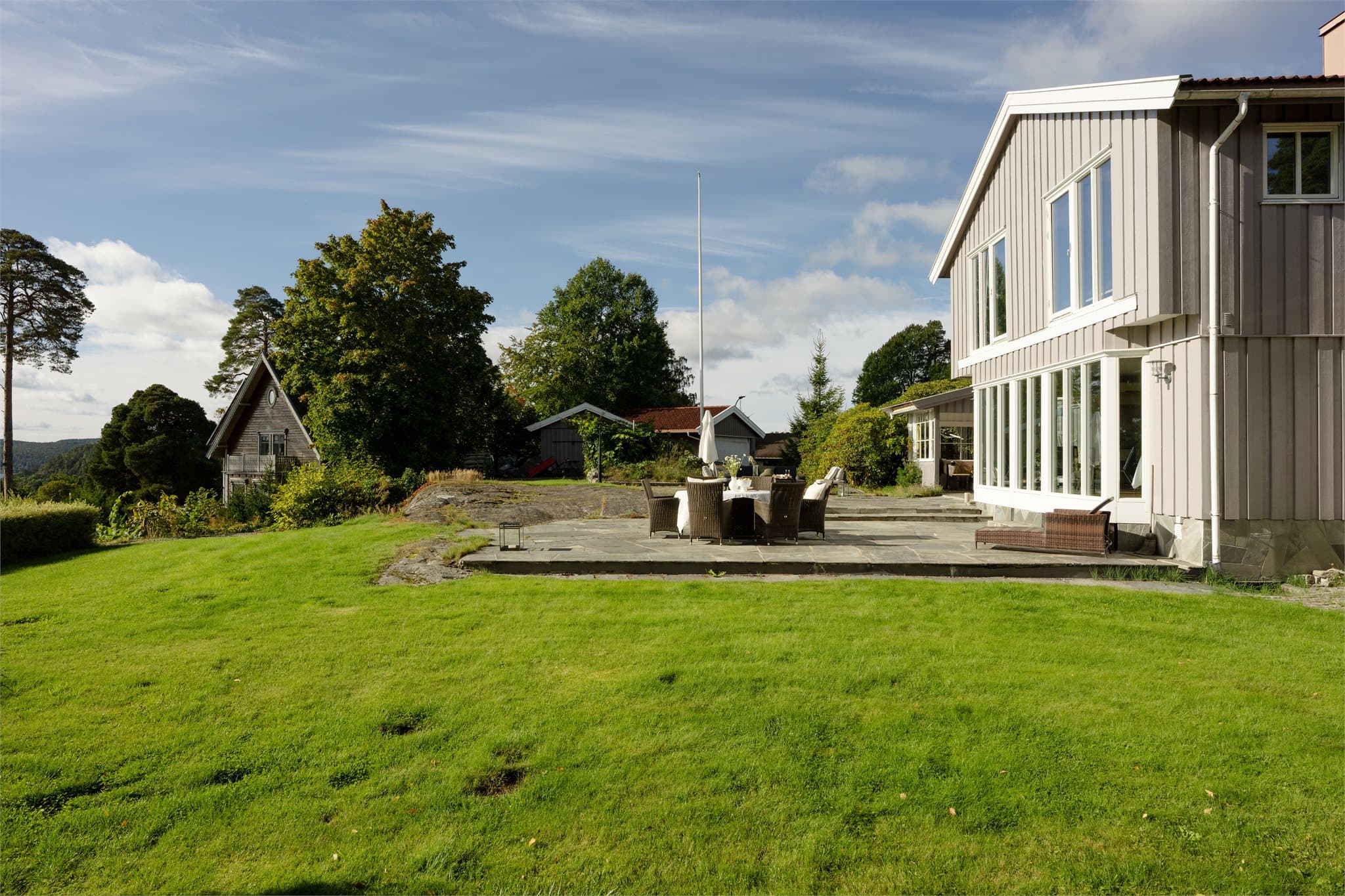 Åpne gressarealer omkranset av hekker og naturtomt.