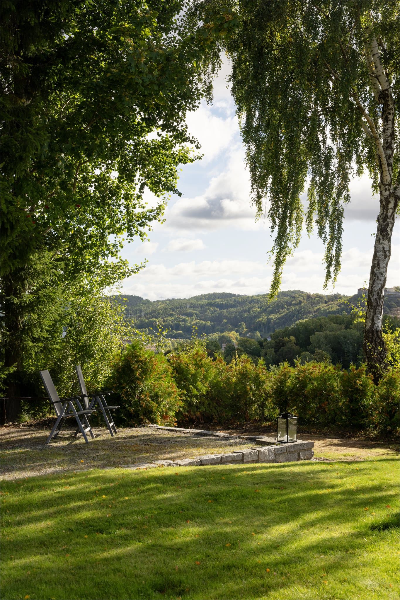 Utsiktsplass i hagen med fri sikt mot åsene og byen nedenfor.