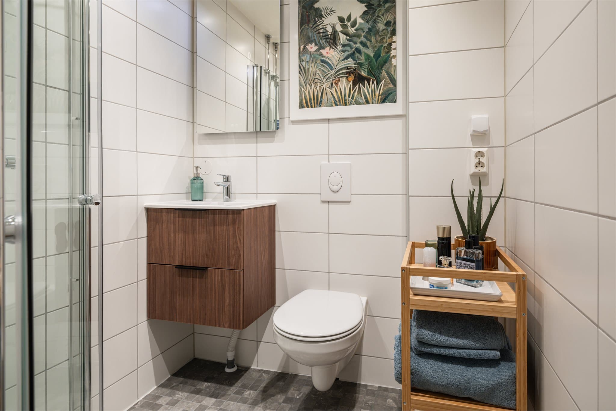 Badet er helfliset med vegghengt toalett og servant med underskap.