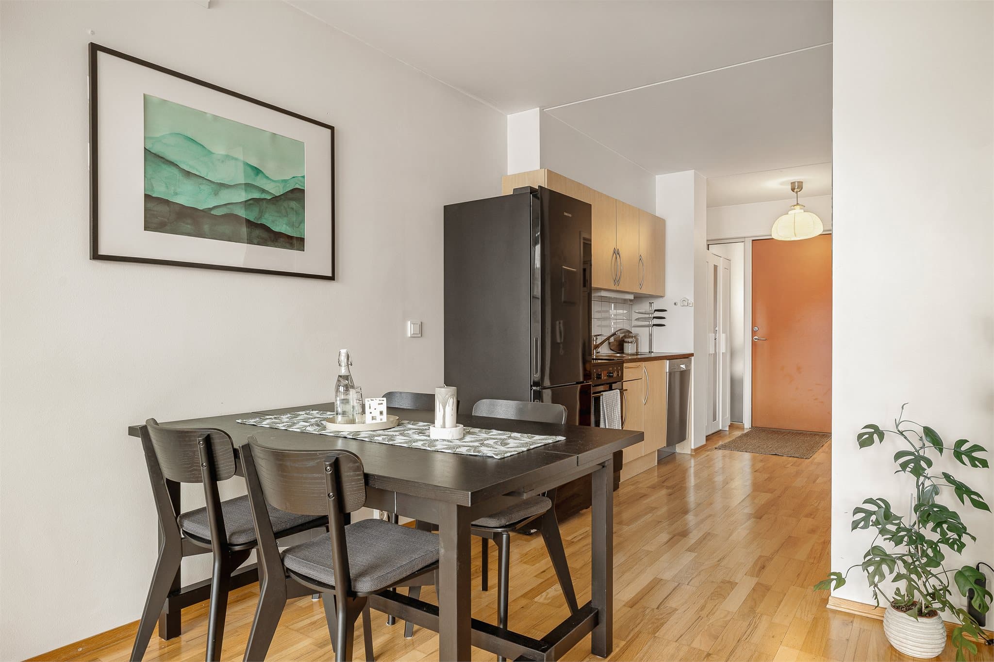 Delvis åpen stue-/kjøkkenløsning med naturlige soner, der sofakroken er naturlig adskilt fra kjøkkenet.