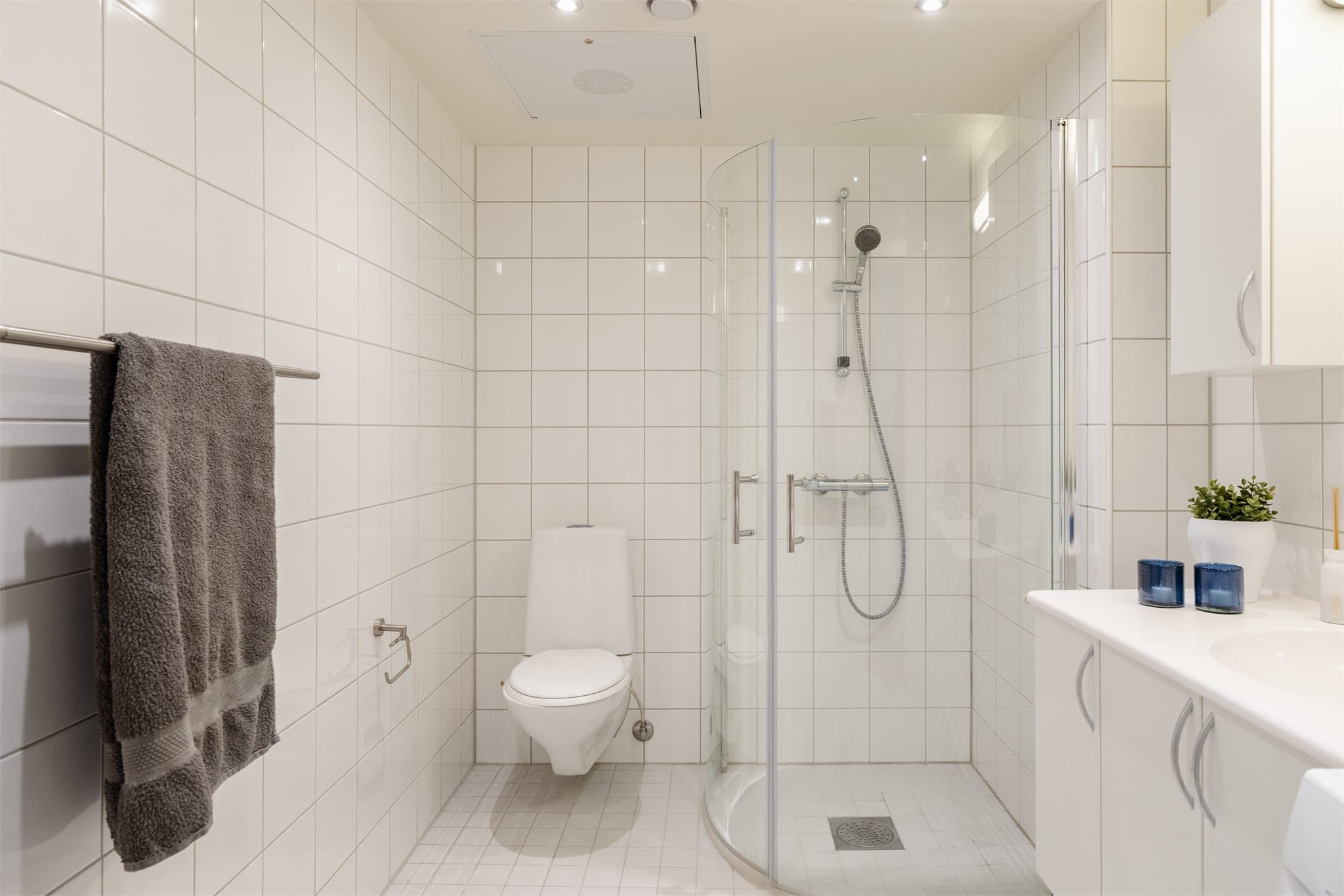 Badet er innredet med servant, klosett, dusj på gulv og opplegg for vaskemaskin.