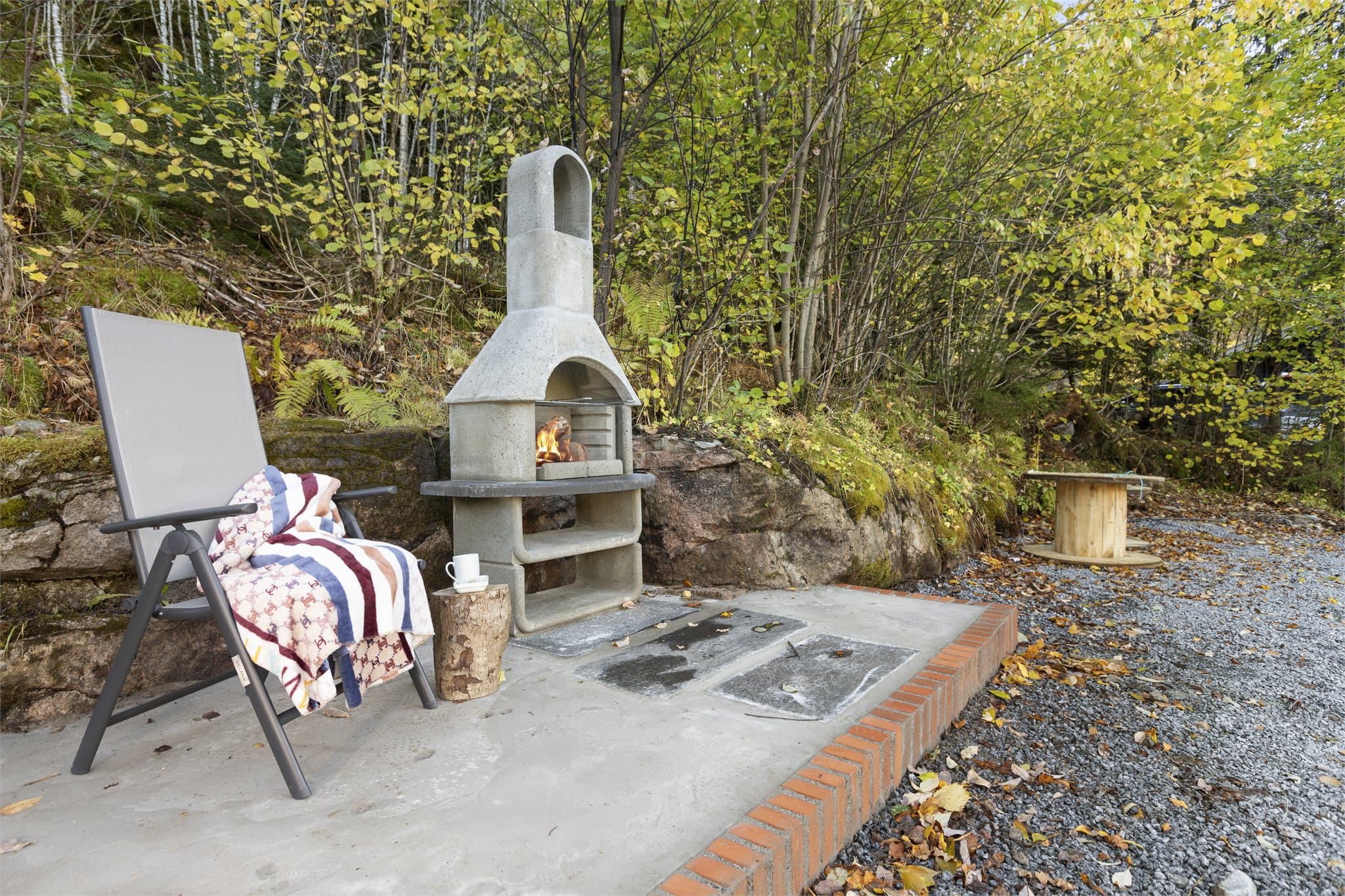 Uteområdet byr også på en betongplatting med grill, lunt plassert langs skogholtet.