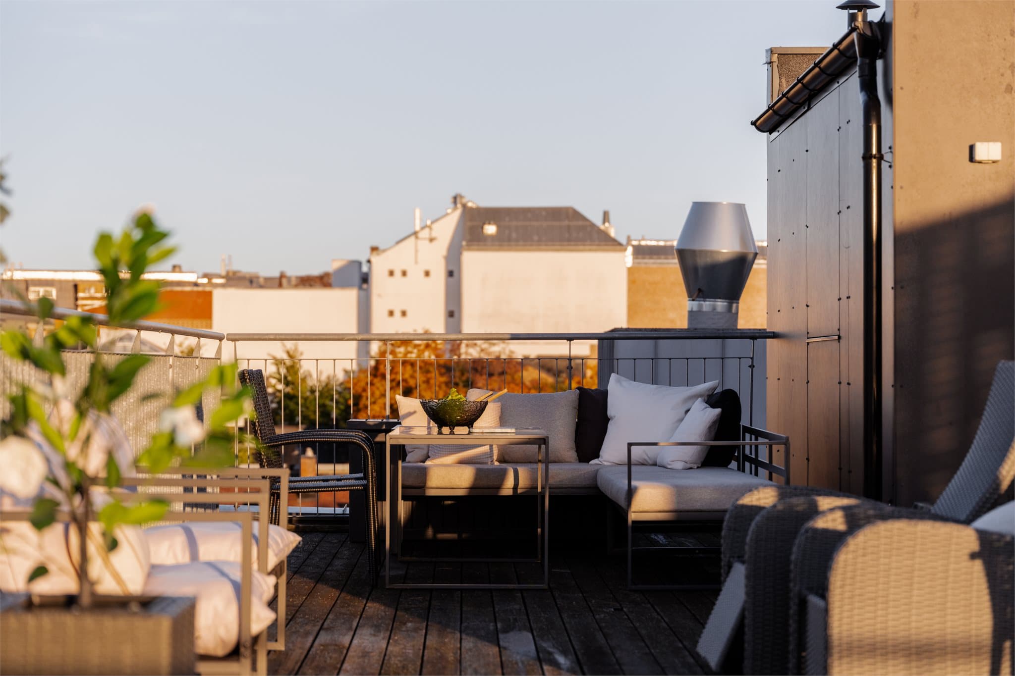 Skjermet hjørne på takterrassen innredet med utendørs sofagruppe.