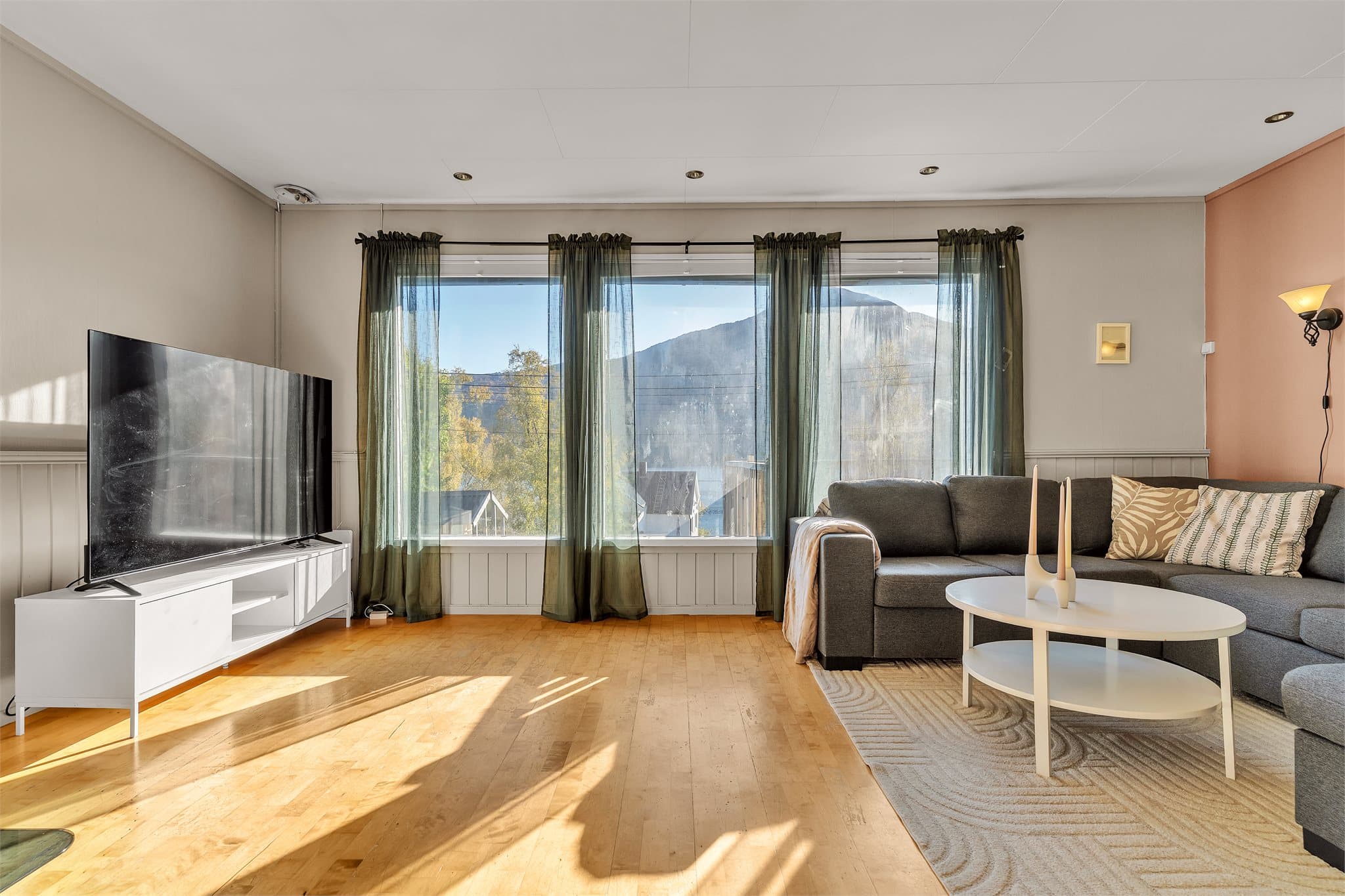 Lys stue med store vindusflater som rammer inn fjellutsikten.