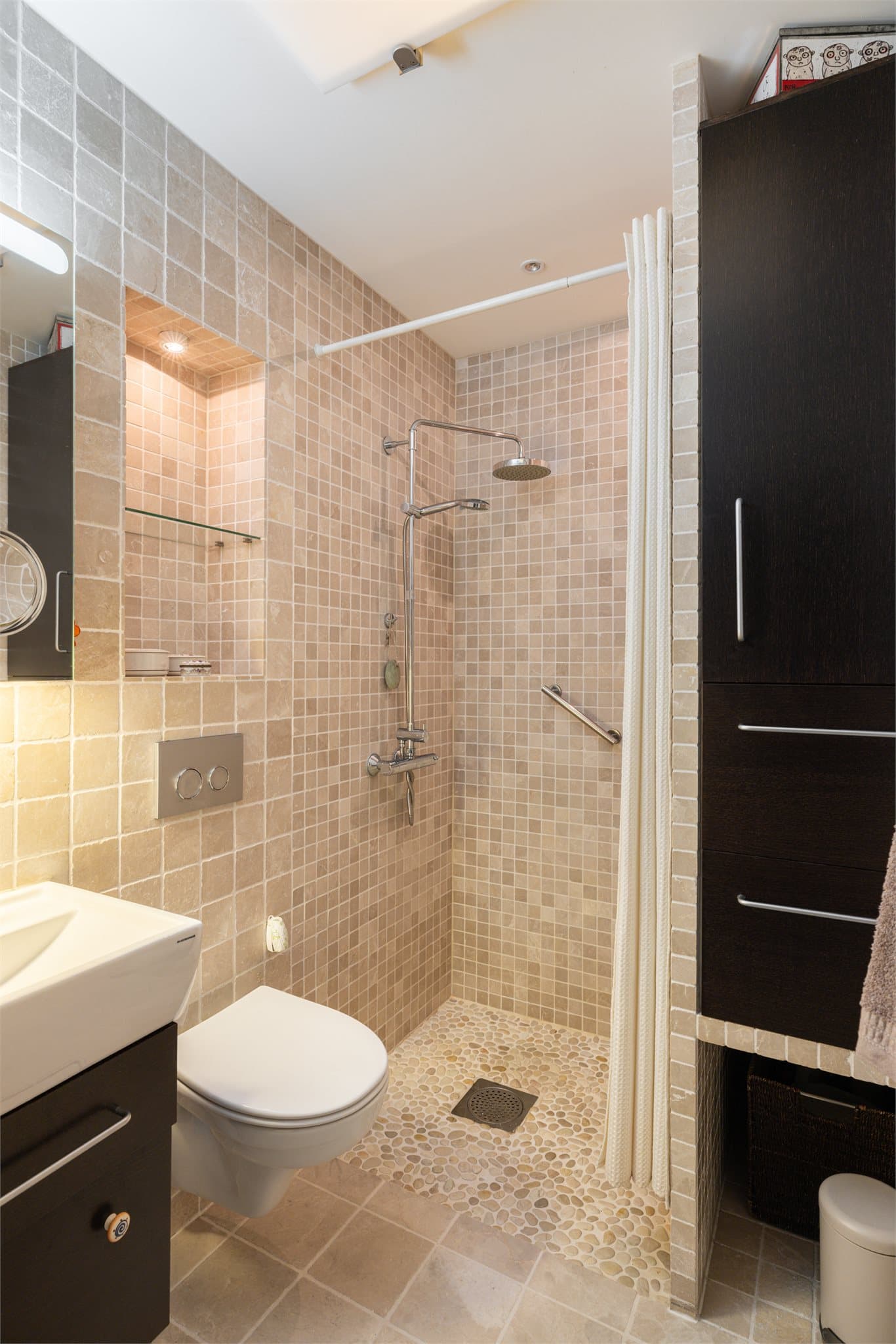 Badet ved soverommet har dusjhjørne med regnfallsdusj, servantskap, speilskap med lys, elektrisk håndkletørker og vegghengt toalett.