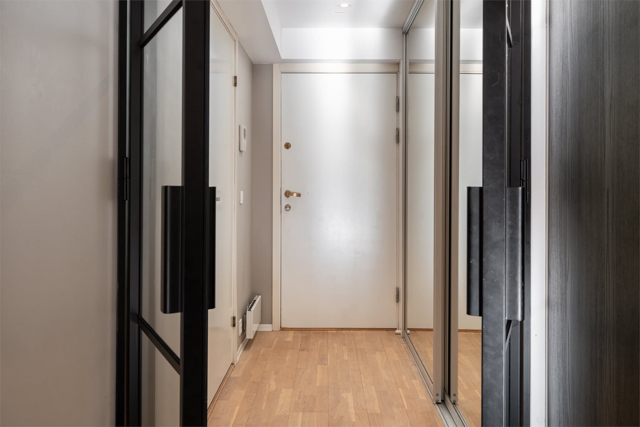 Romslig og innbydende entré med gode oppbevaringsmuligheter i en praktisk skyvedørsgarderobe med speilfronter.