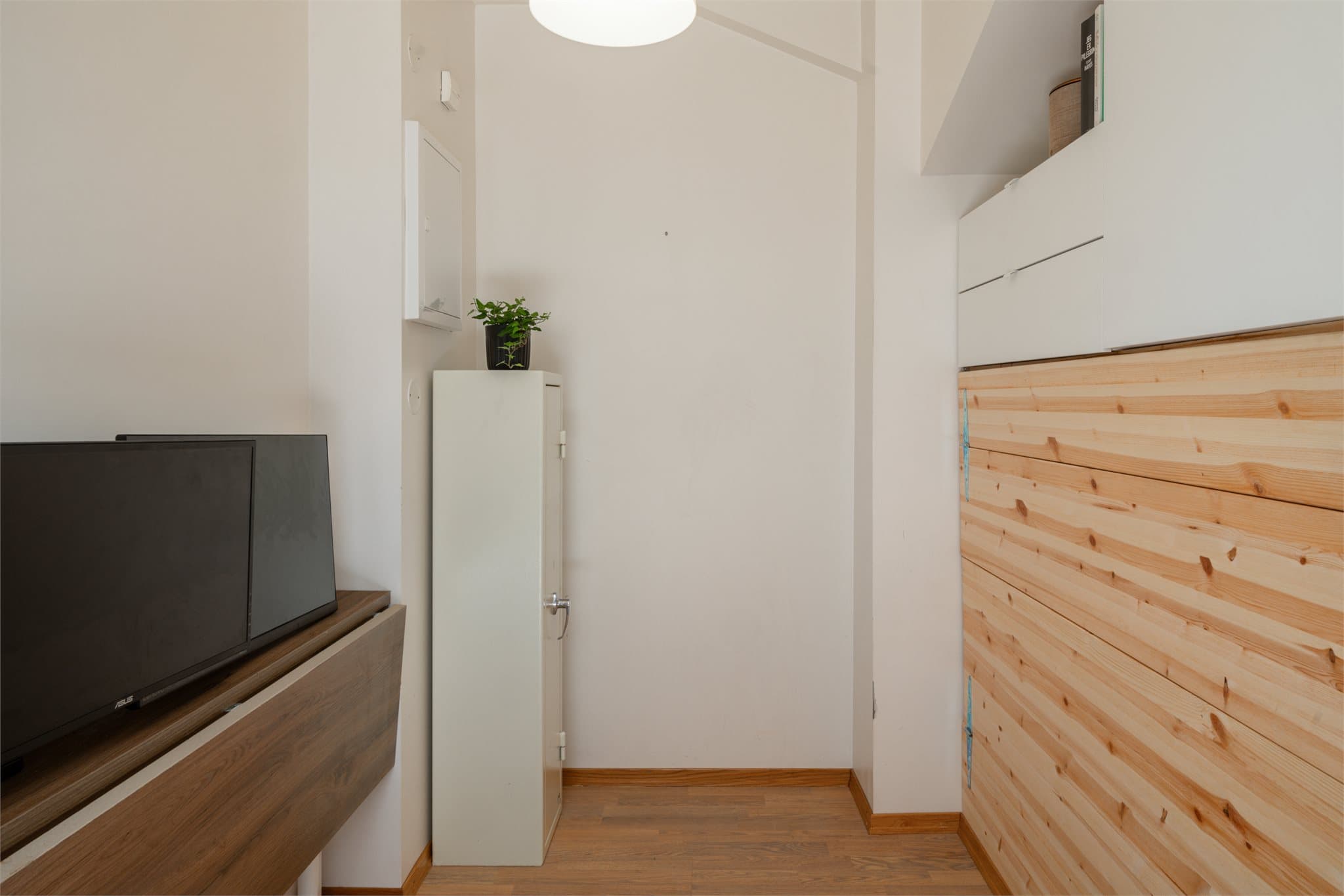 Rommet har en smart, plassbygget møbelløsning med seng som kan løftes opp og skjules i skapinnredningen.